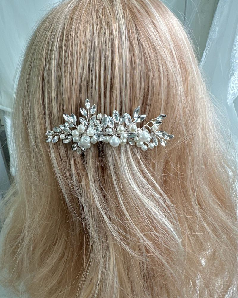Silver hair comb with pearls in blonde hair against a white background