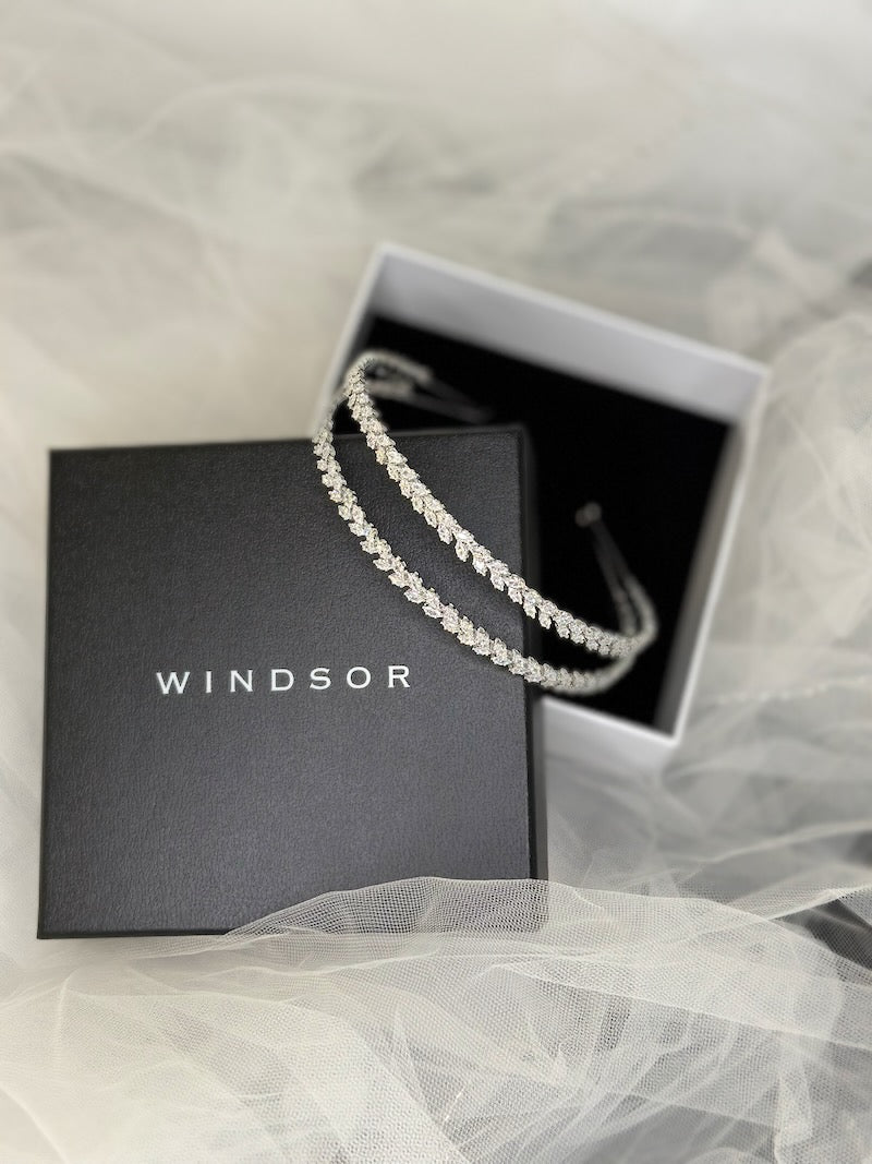 a two row silver crystal headband resting in an open box