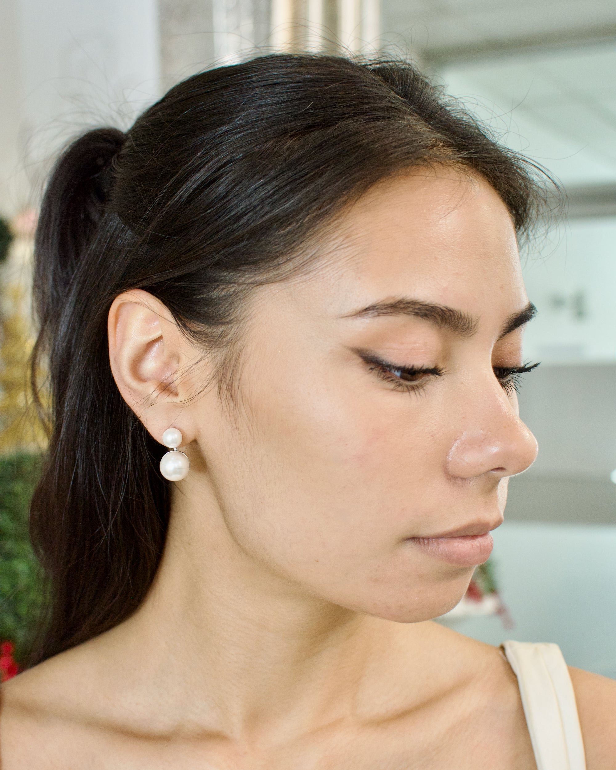 Woman wearing pearl earrings with a blurred background