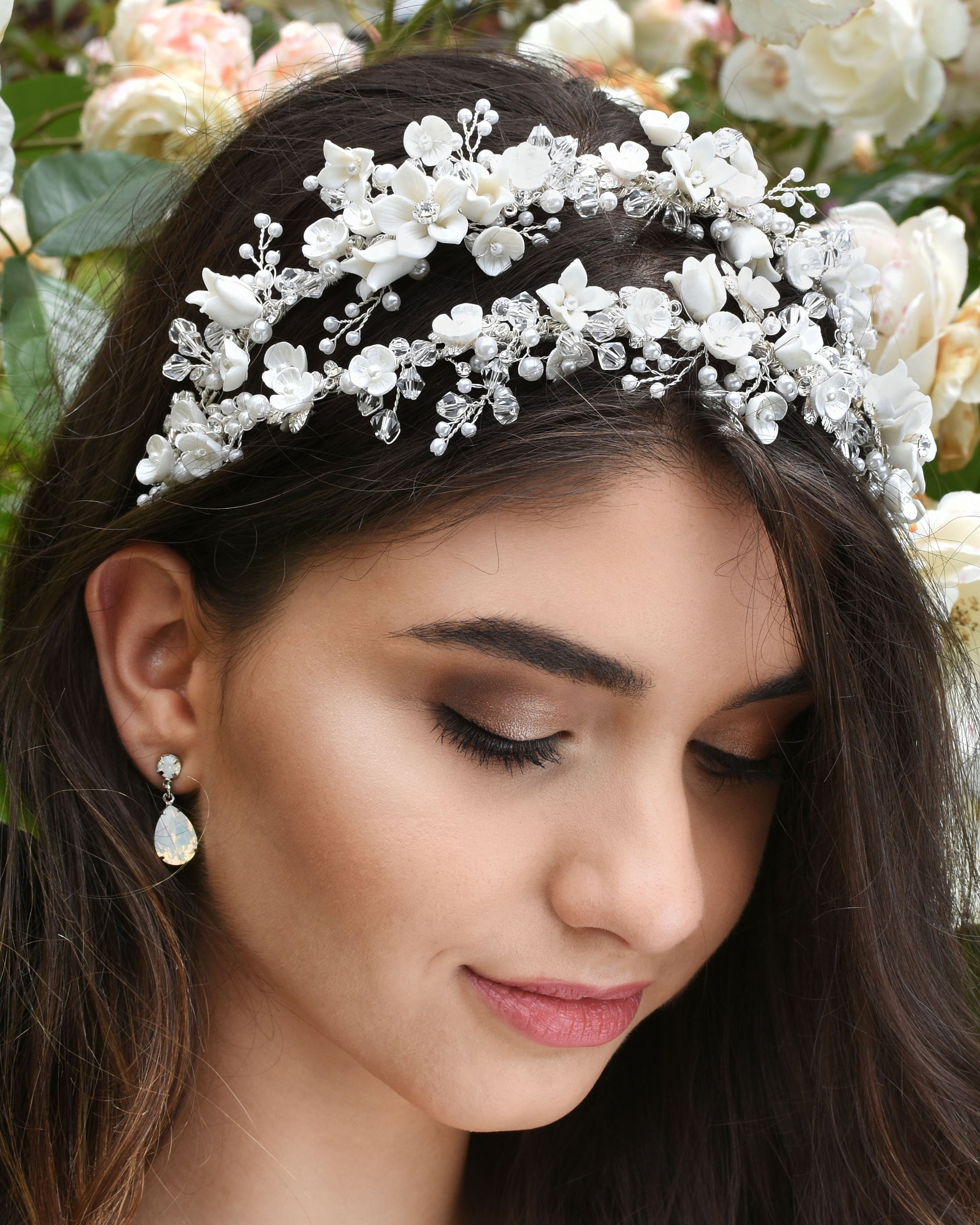 Dark hair bride wears a double row headband of ceramic flowers with a background of white roses