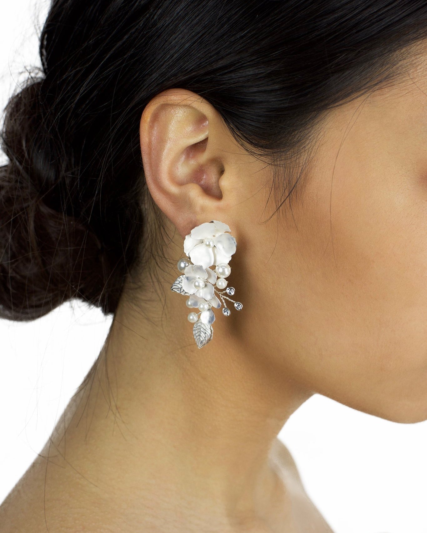 Silver hand painted earrings with pearls worn by a dark haired model bride