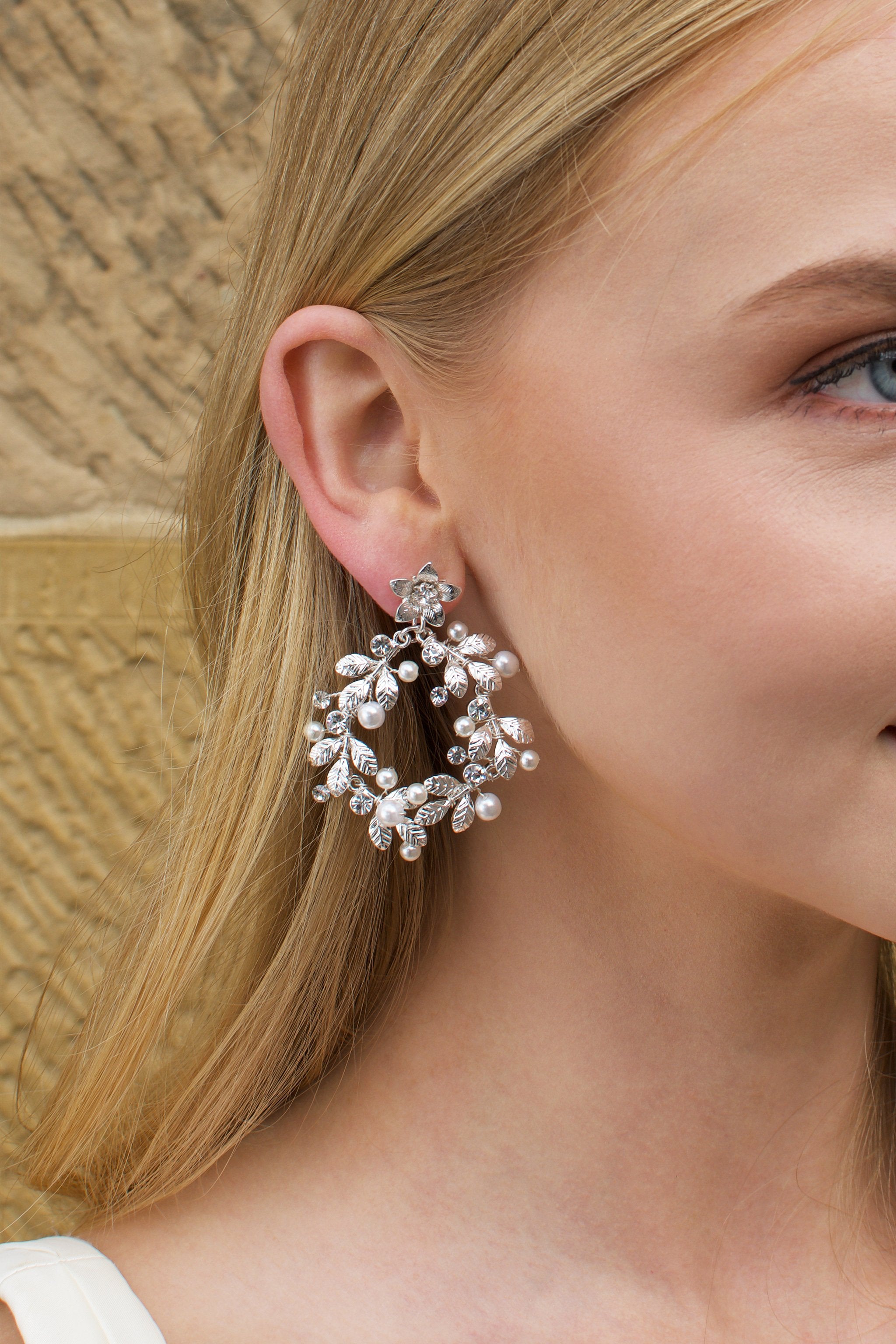 Model with Blonde hair wears a silver hoop shape earring in her ear.
