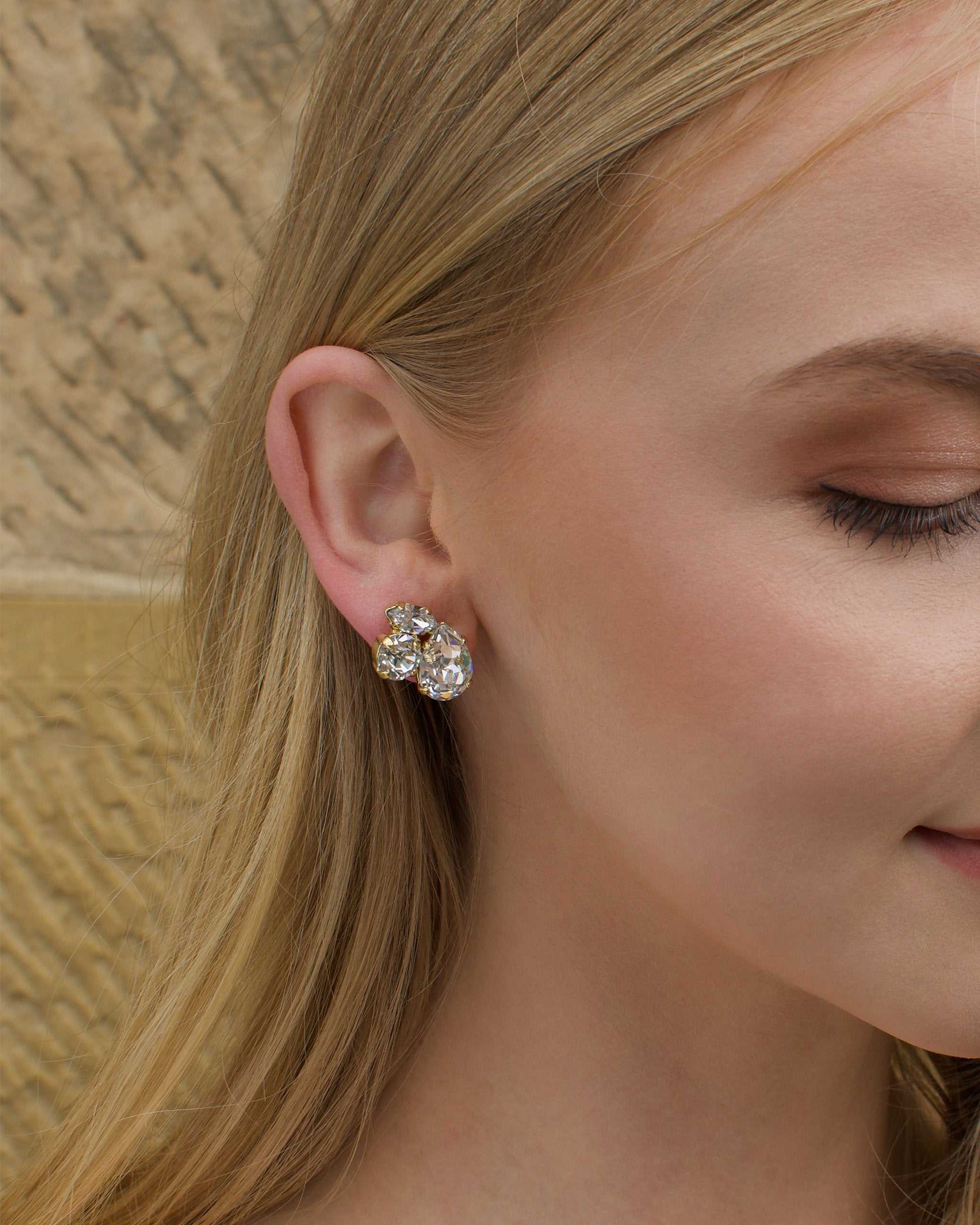 Clear stones in a gold hand made earring worn by a blonde model bride