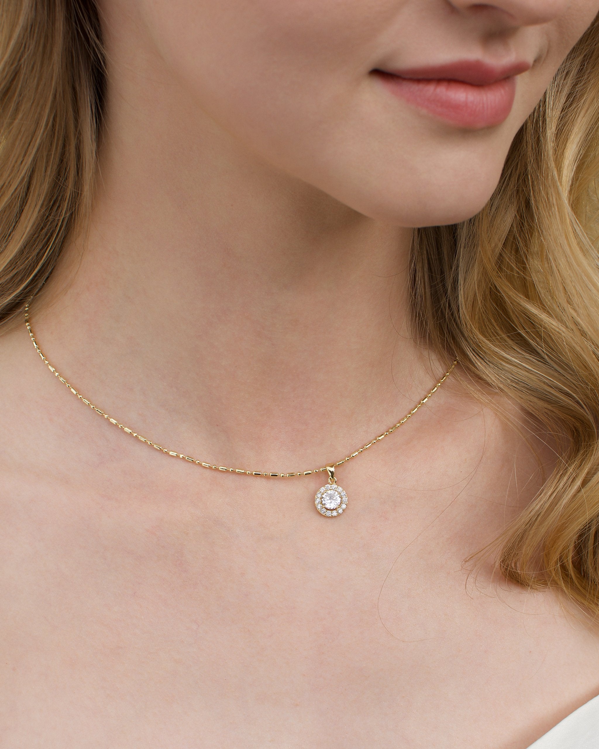A gold chain around the neck of a model with a single hanging stone