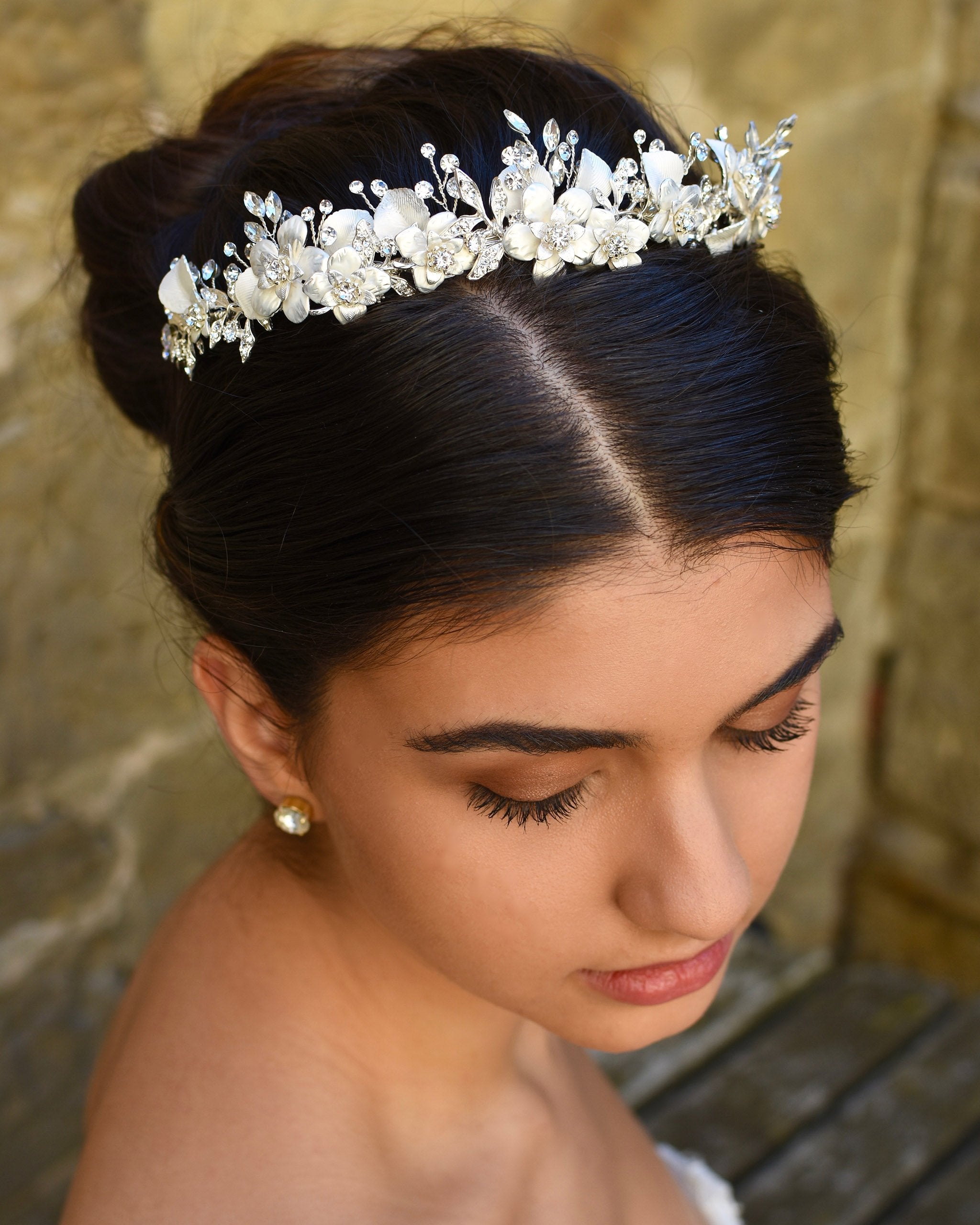White and silver Bridal headpiece is worn by a dark hair model with a stone wall backdrop
