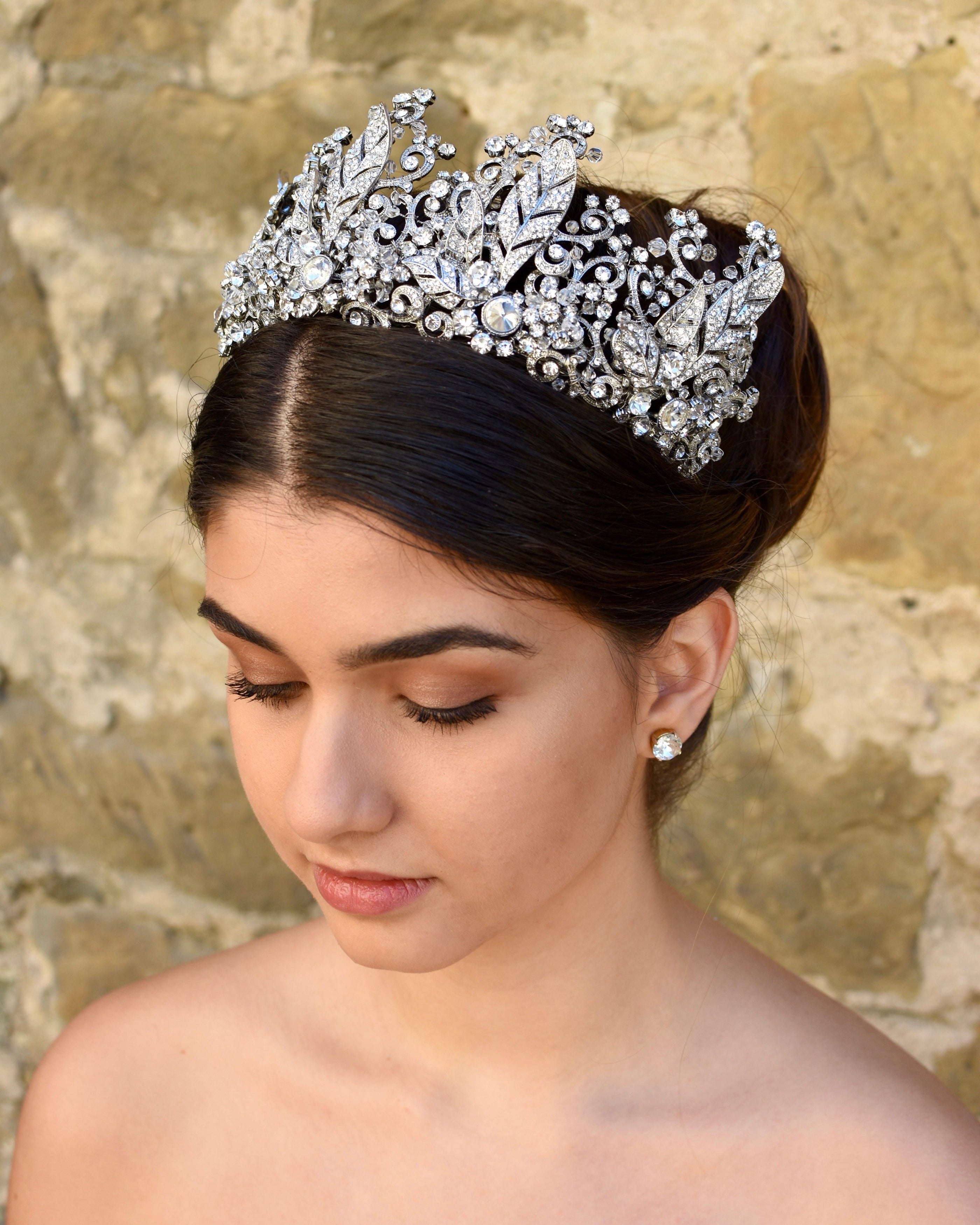 A Tall Bridal Tiara in Silver worn by a Dark Hair Bride with an old stone wall background