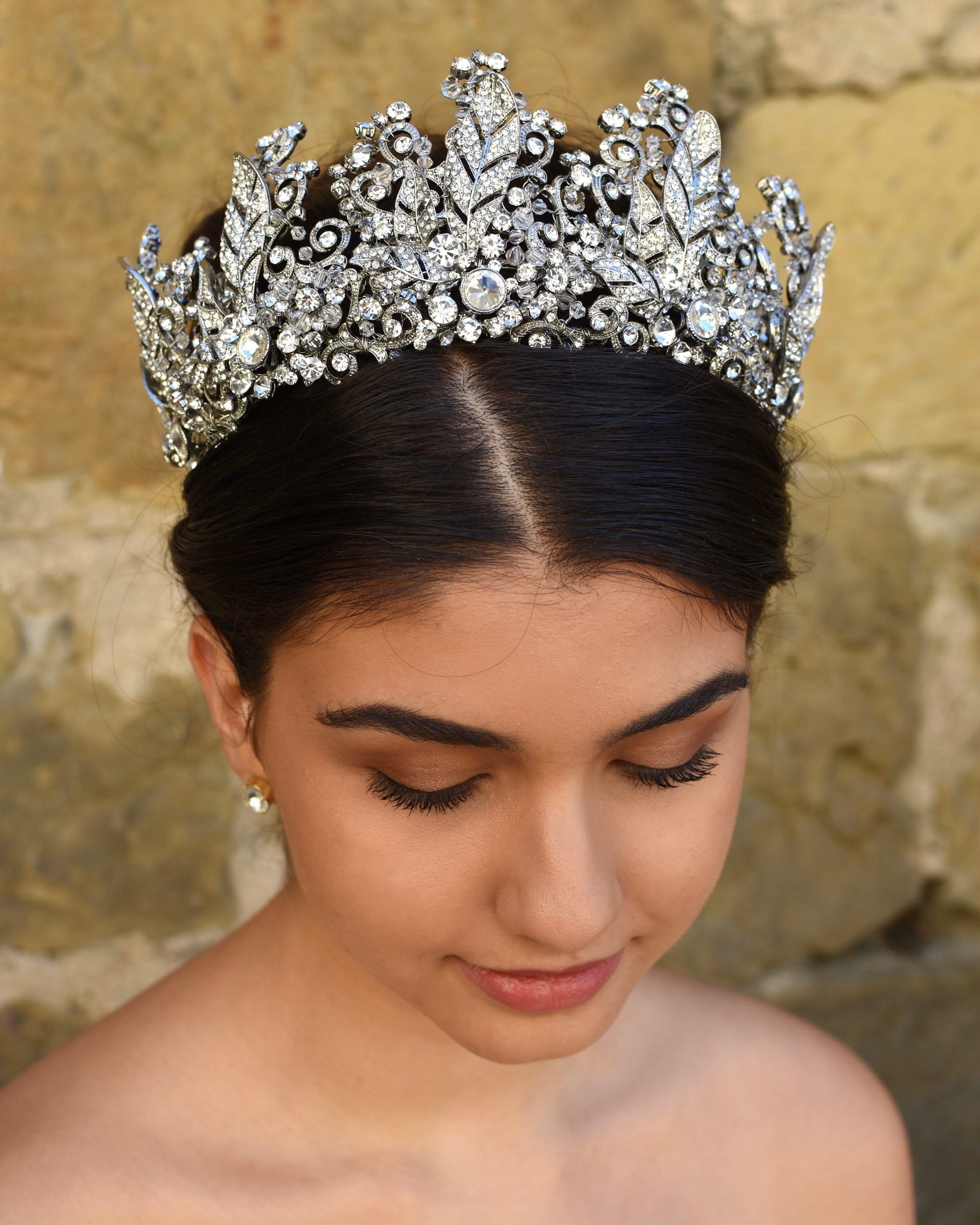 A high many points crown worn by a dark hair model with an old sandstone wall backdrop