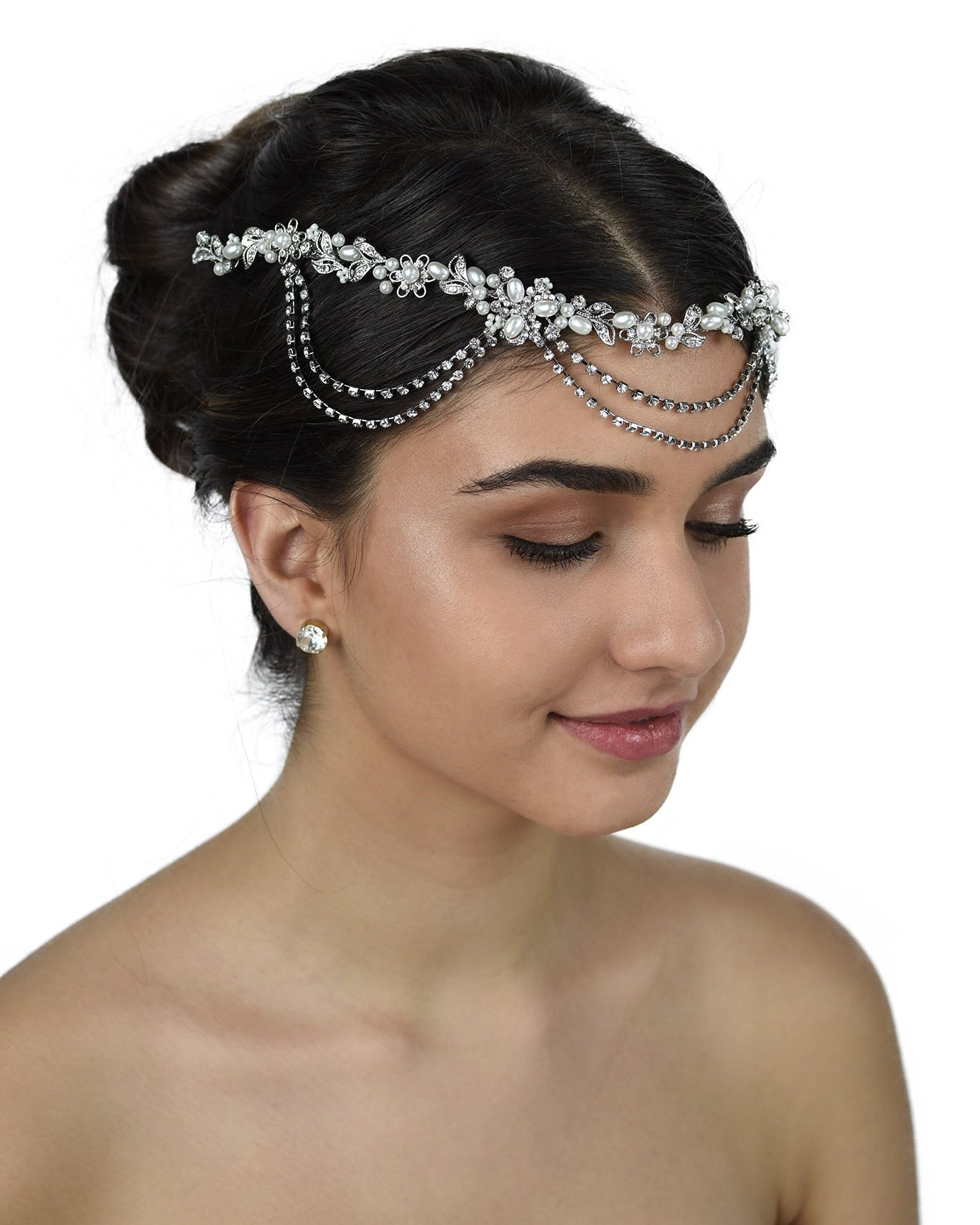 A bride wears a pearl and rhodium vine with loops on her forehead with a white background