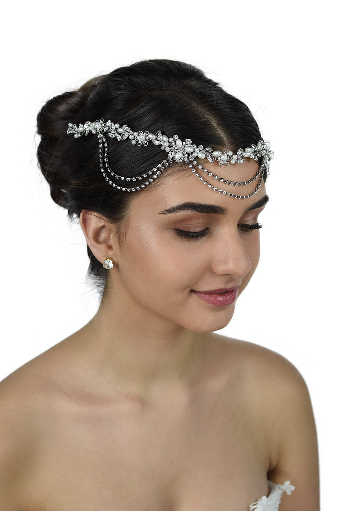 A bride wears a pearl and rhodium vine with loops on her forehead with a white background