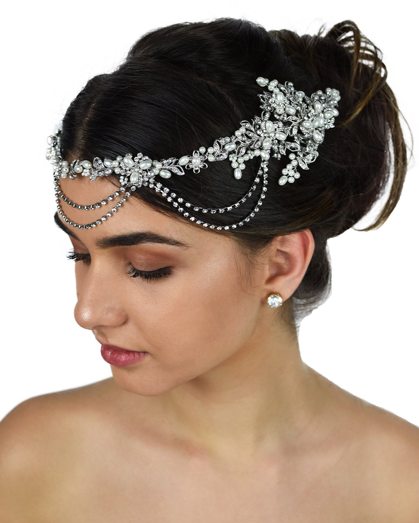 A dark hair model with her hair up wears a pearls and rhodium bridal vine at the front of her head. With a white background