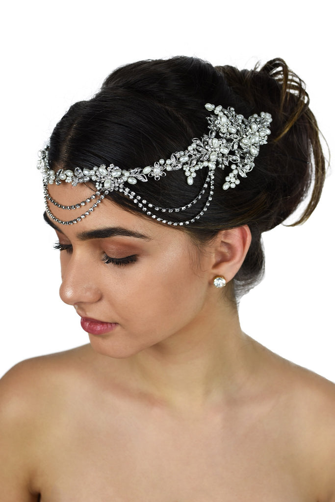 A dark hair model with her hair up wears a pearls and rhodium bridal vine at the front of her head. With a white background