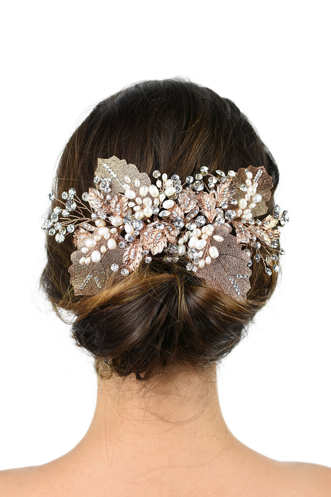 Brown hair model bride wears a large leaves bridal headpiece at the back of her head on a white background