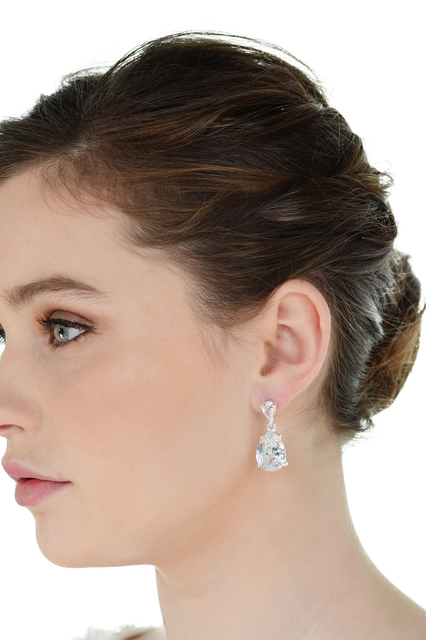 Dark haired model wearing a pear shaped stone earring against a white background.