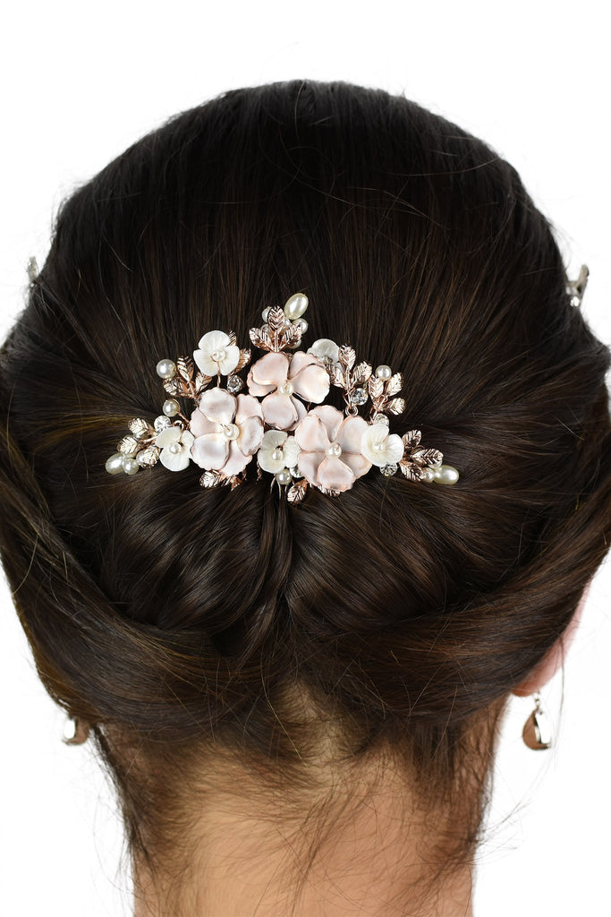The back of  the head of a bride wearing a soft rose gold bridal comb in her dark hair