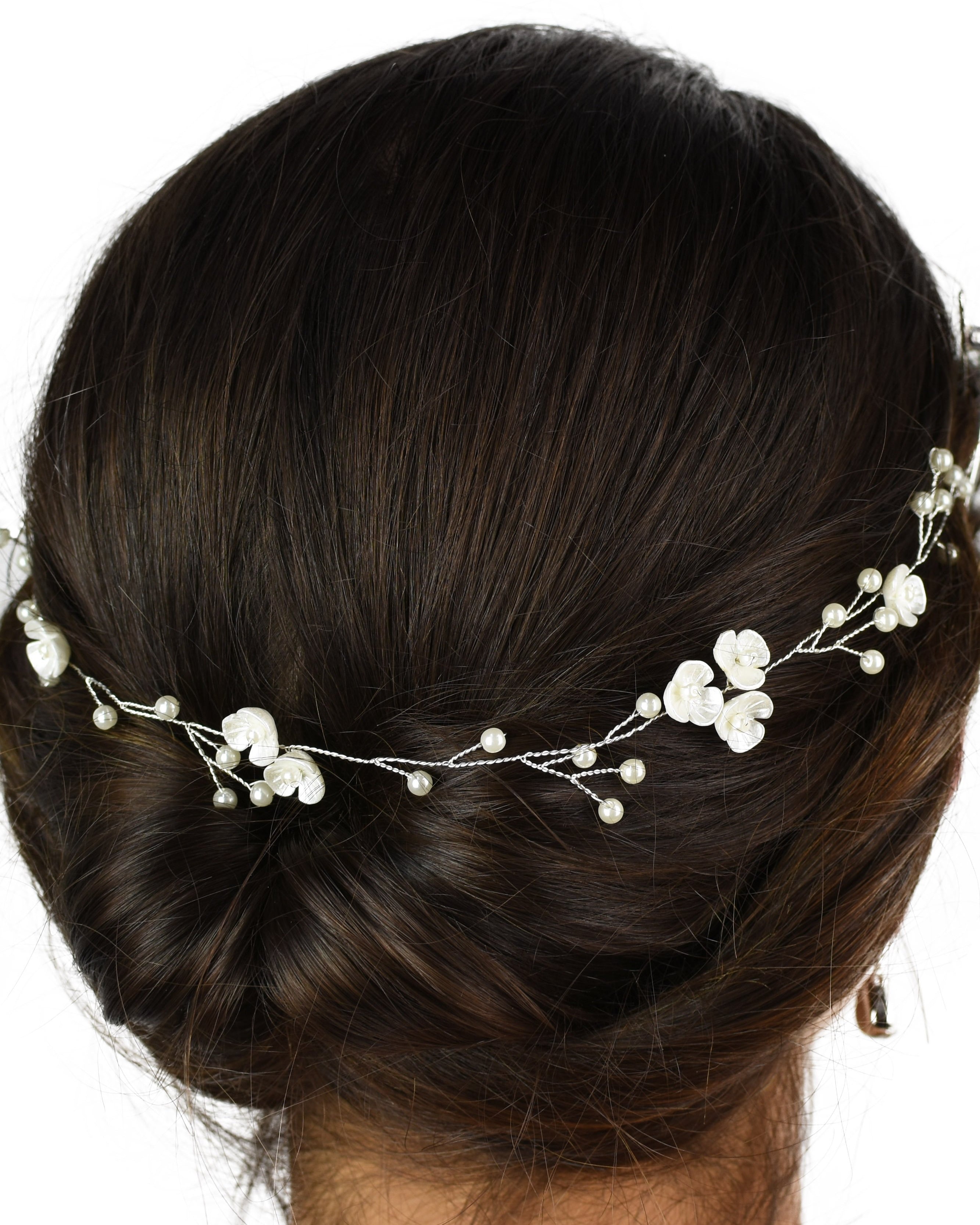 Ceramic Pearl flowers on a thin silver vine worn on a brown hair model with a white background
