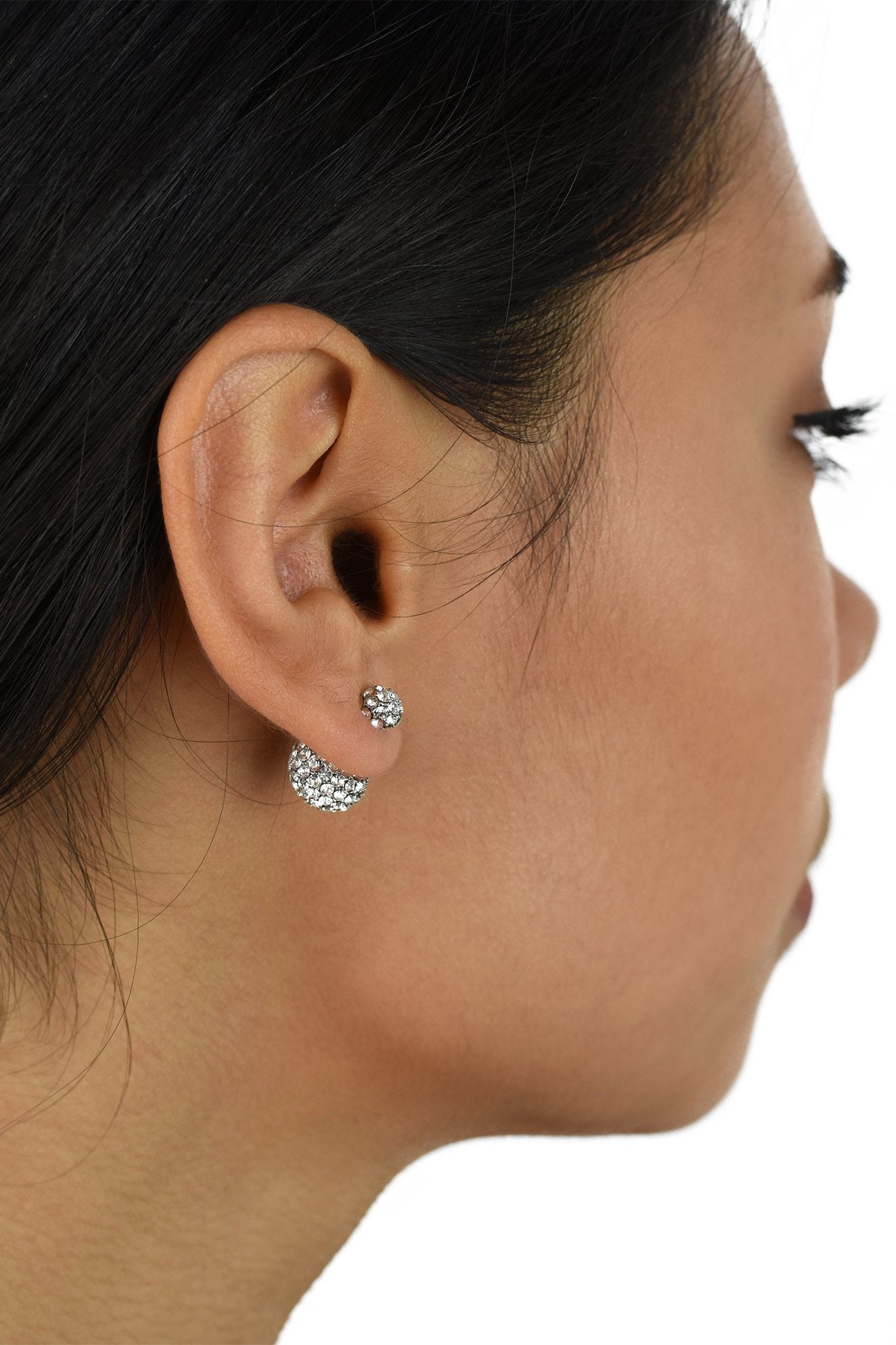 The ear of a dark hair model shows a large crystal ball at the back of the ear with a small crystal ball on the front of the ear.