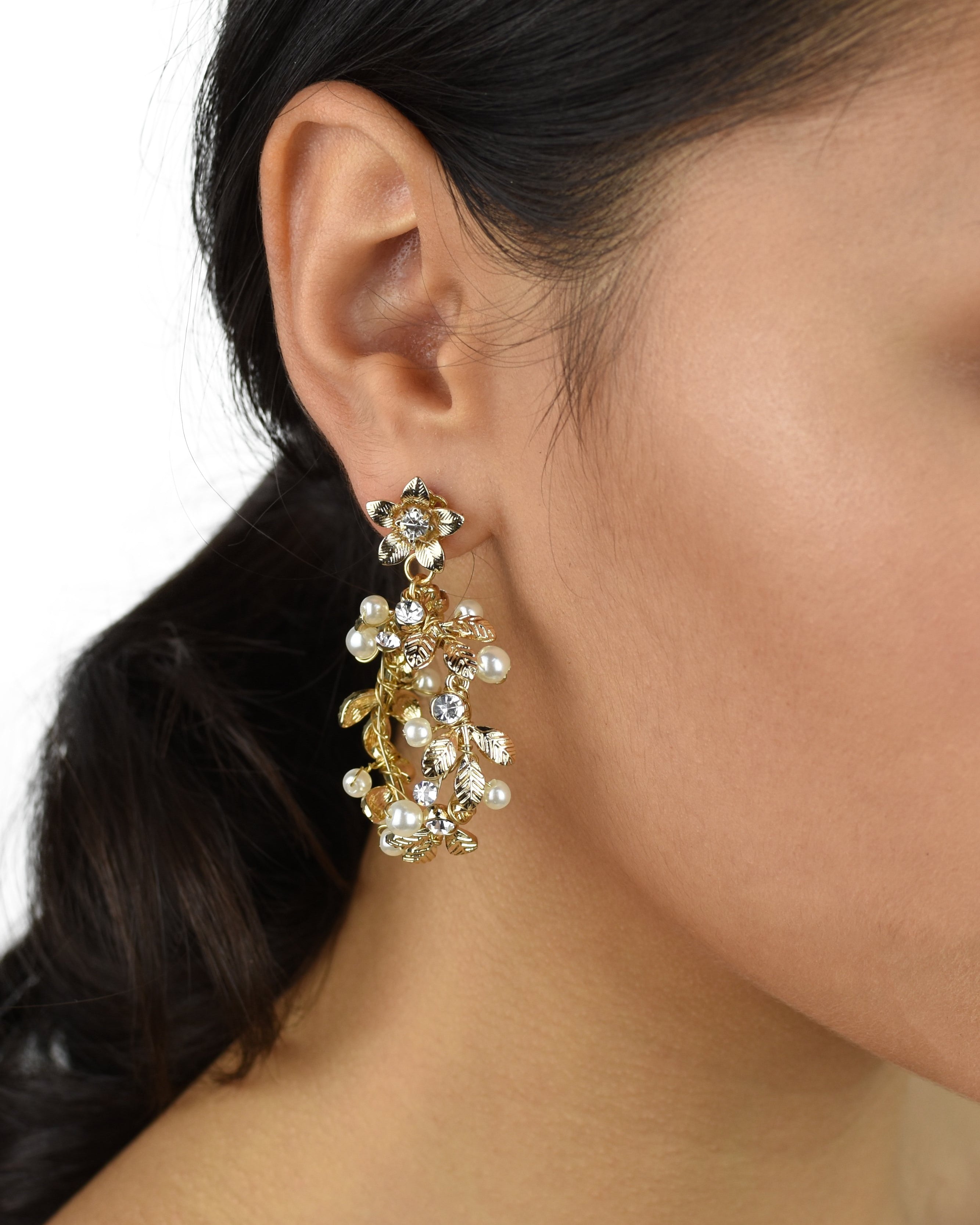 Model wears a gold hoop shape earring in her ear and she has dark hair
