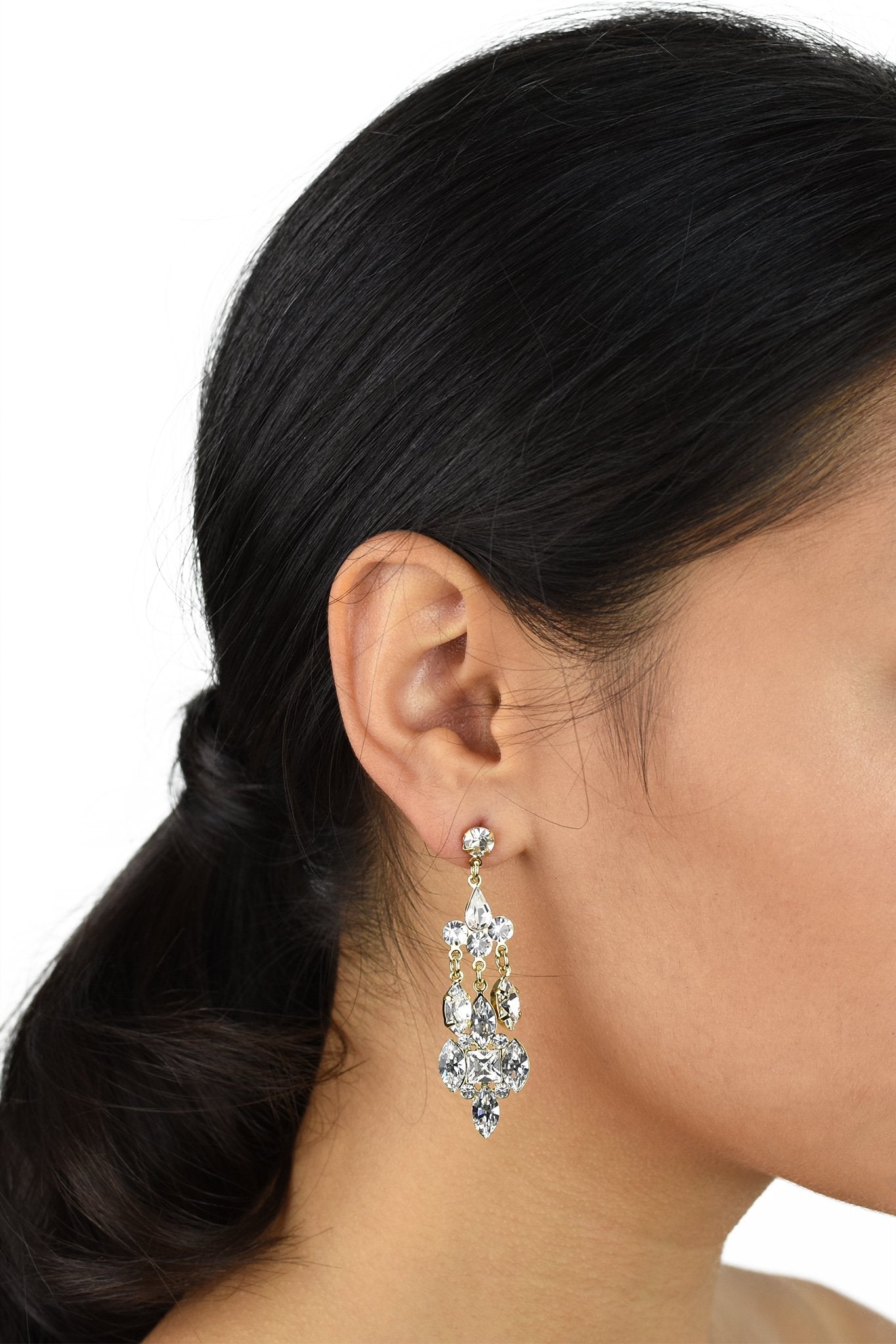 Dark haired Bride wearing a mid length silver drop earring with a post fitting on a white background.