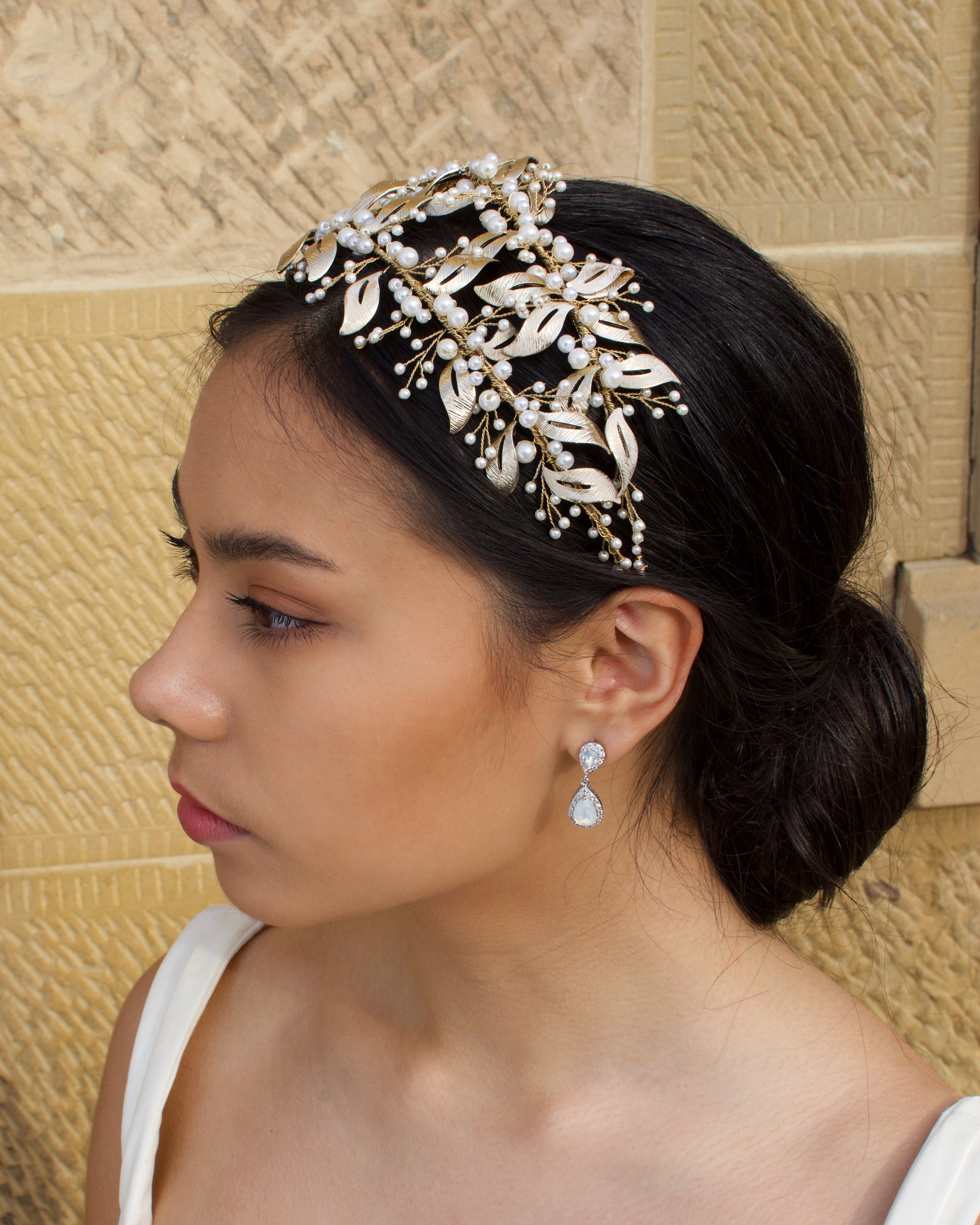 Side View of Double row pale gold headband with pearls worn by a dark hair model with a sandstone wall