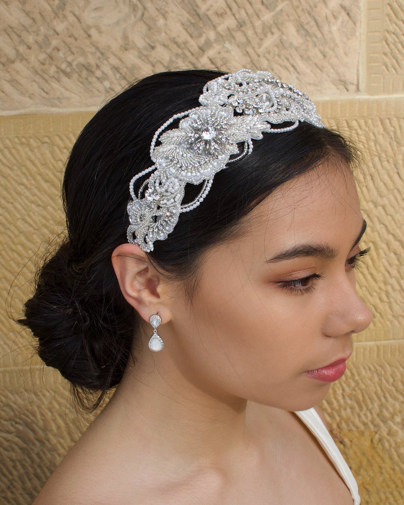 Seed Pearl wide headband worn by a black hair bridal model with a stone background