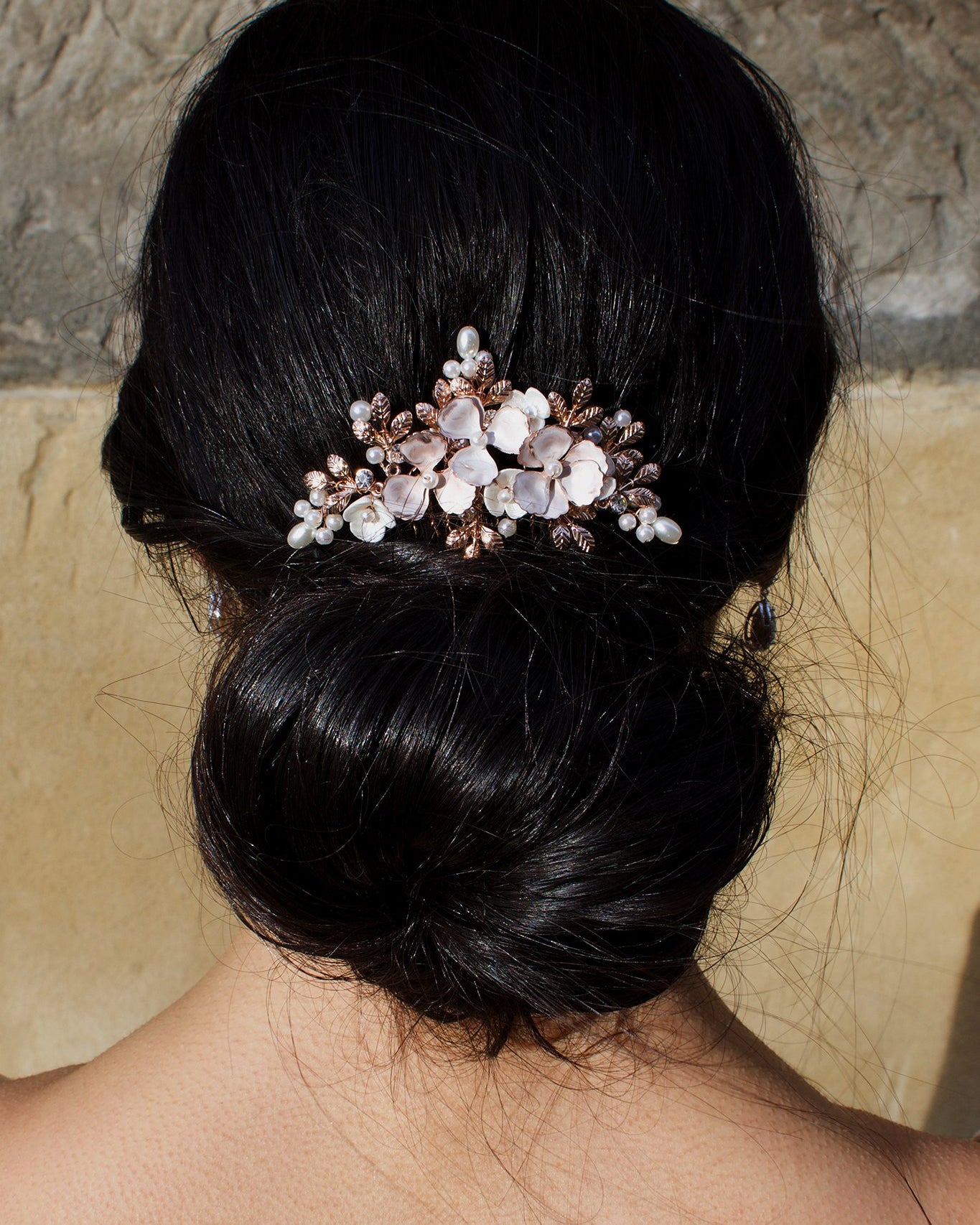 A black hair model wearing a pale rose gold comb above a bun of hair