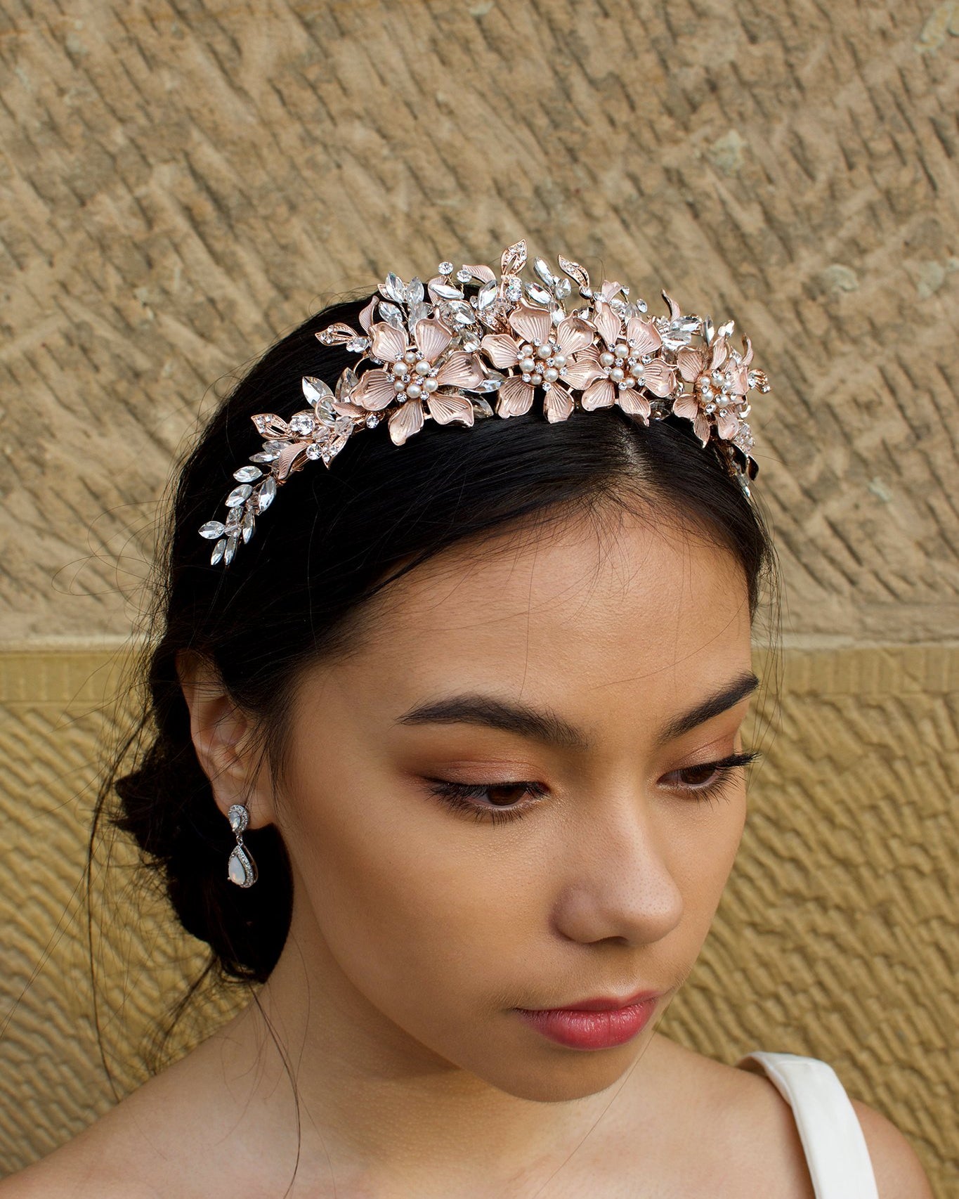 Pale Rose Gold Flowers and Leaves Tiara with pearls worn by a dark hair bride in front of a stone wall