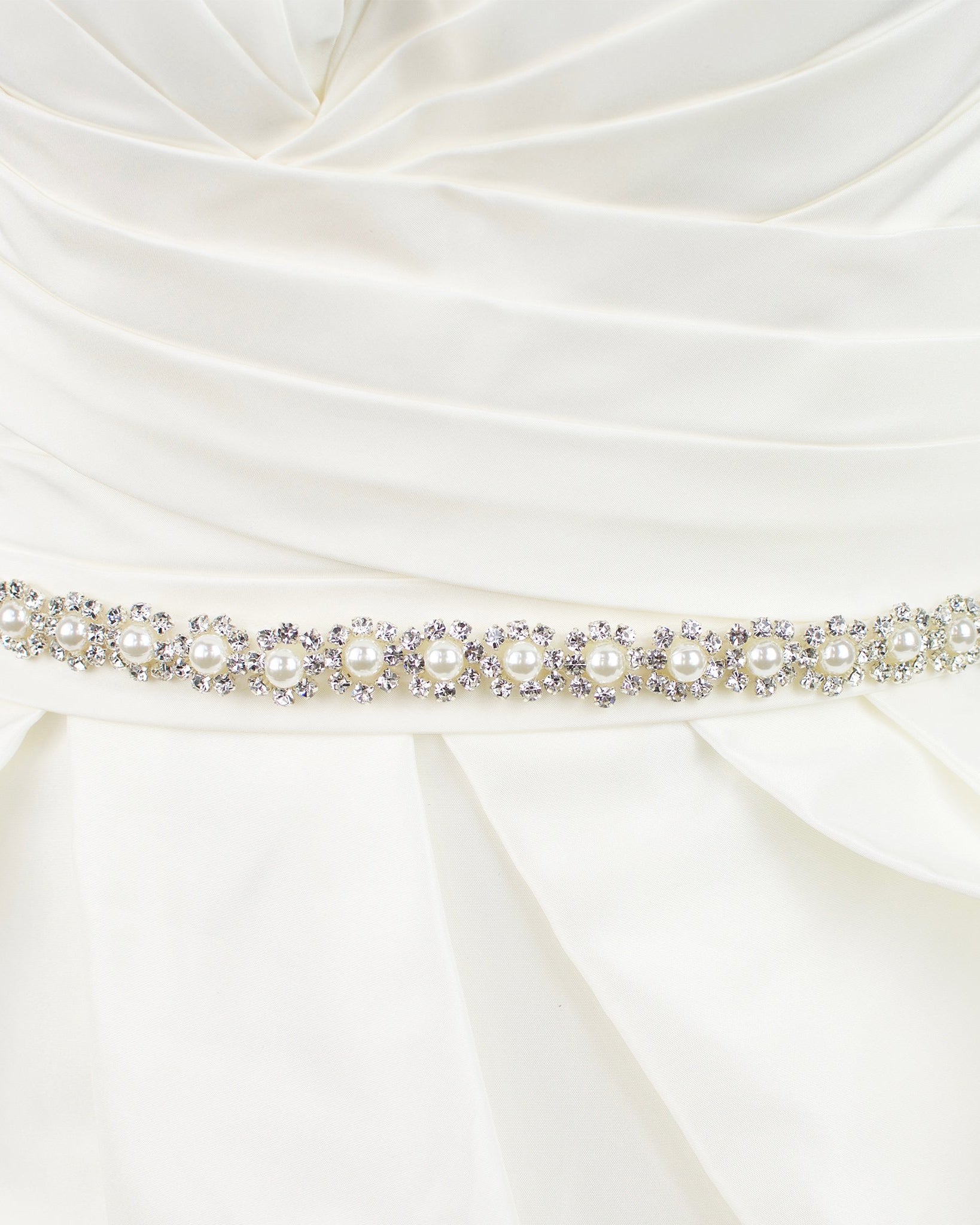 A narrow pearl bridal belt with rings of crystals around the pearls is worn on an ivory bridal gown