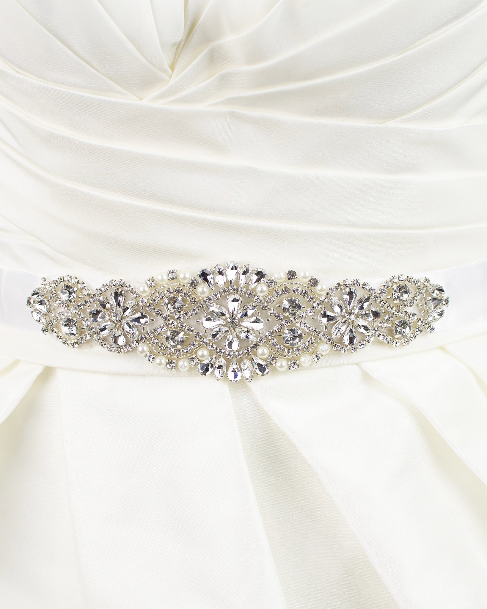 A bridal belt with crystals and pearls that is quite short on a satin ribbon worn on an ivory bridal gown