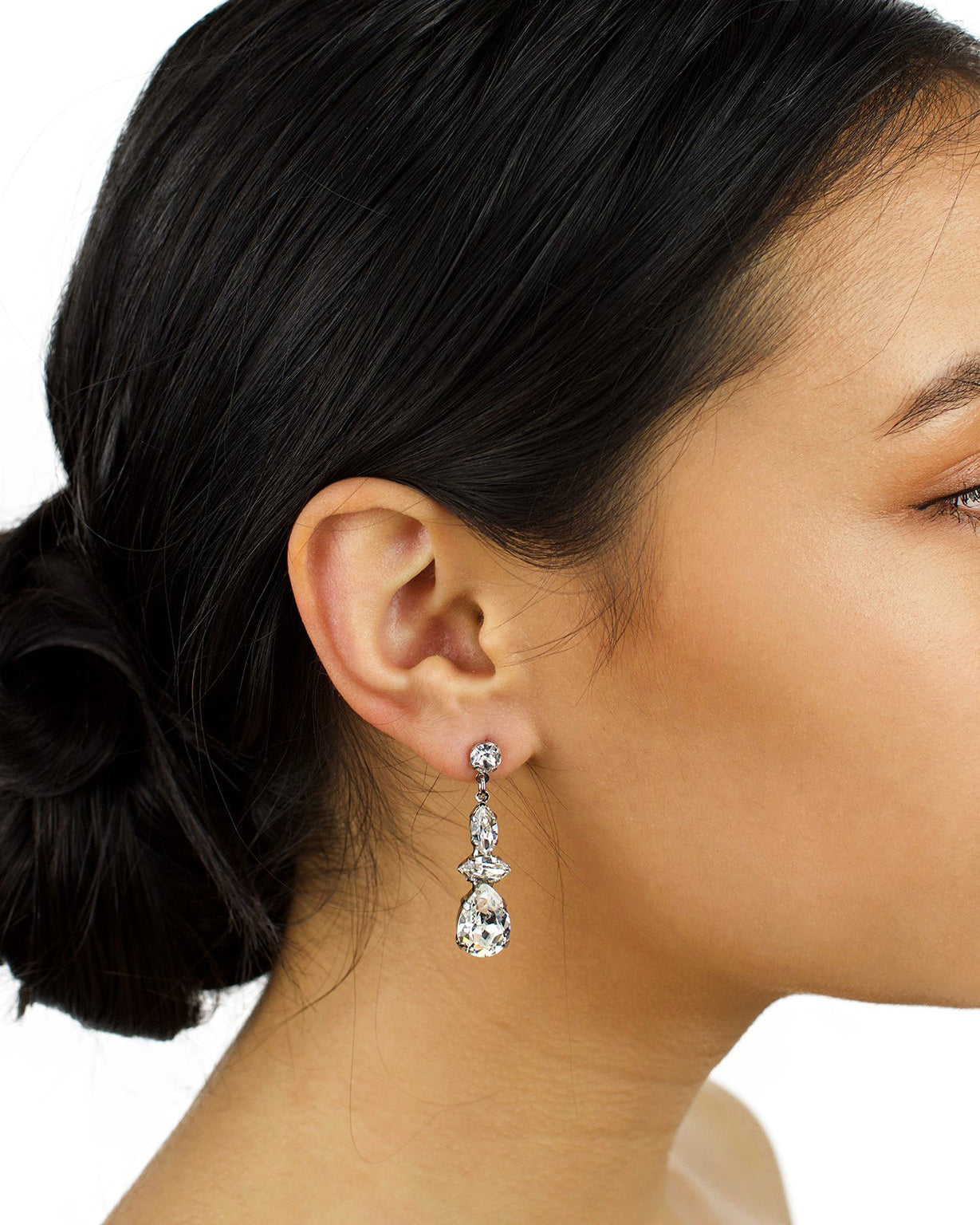 Dark hair model wearing a short Swarovski Crystal drop earring with a white background