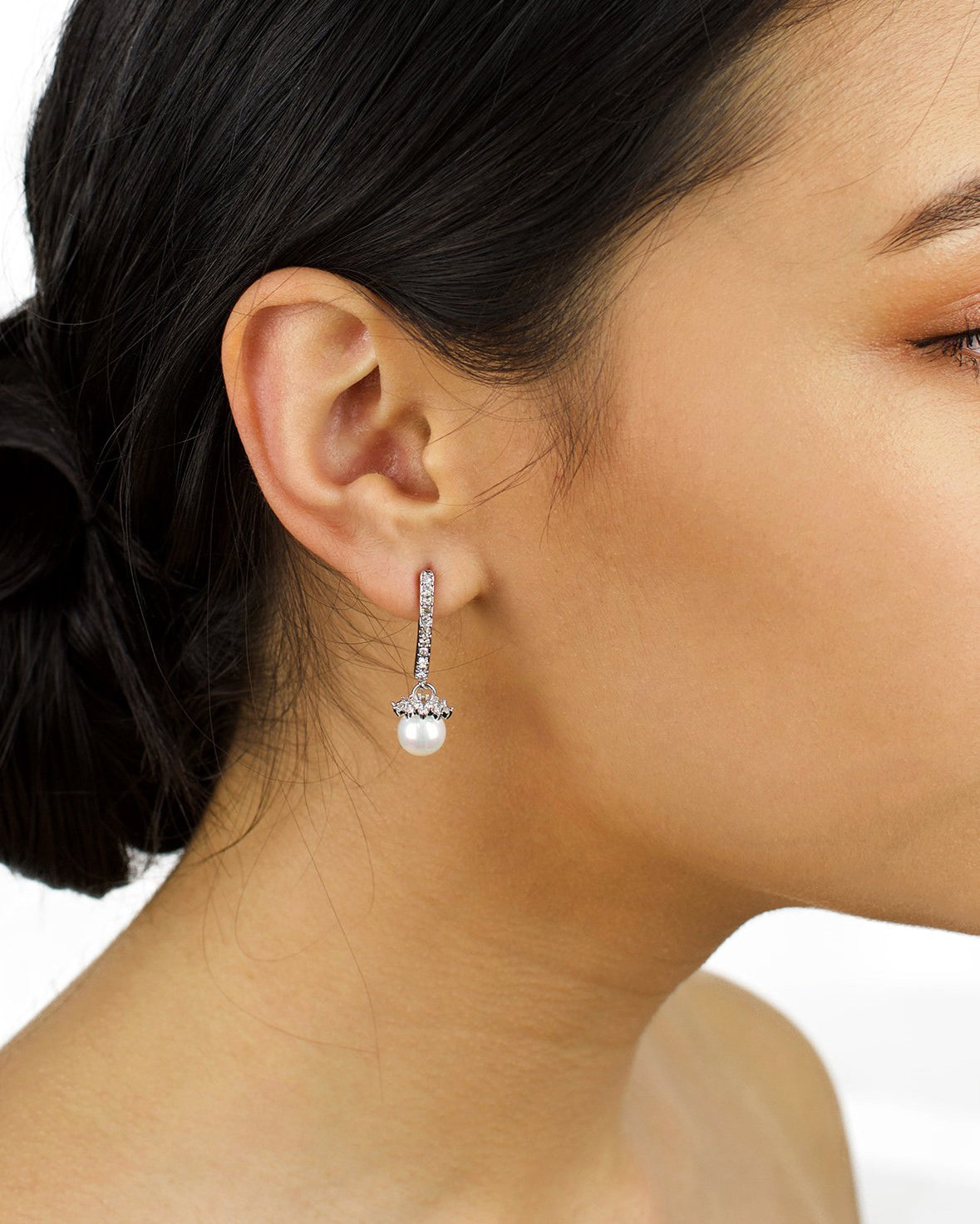 A dark hair model with a drop pearl earring in her ear
