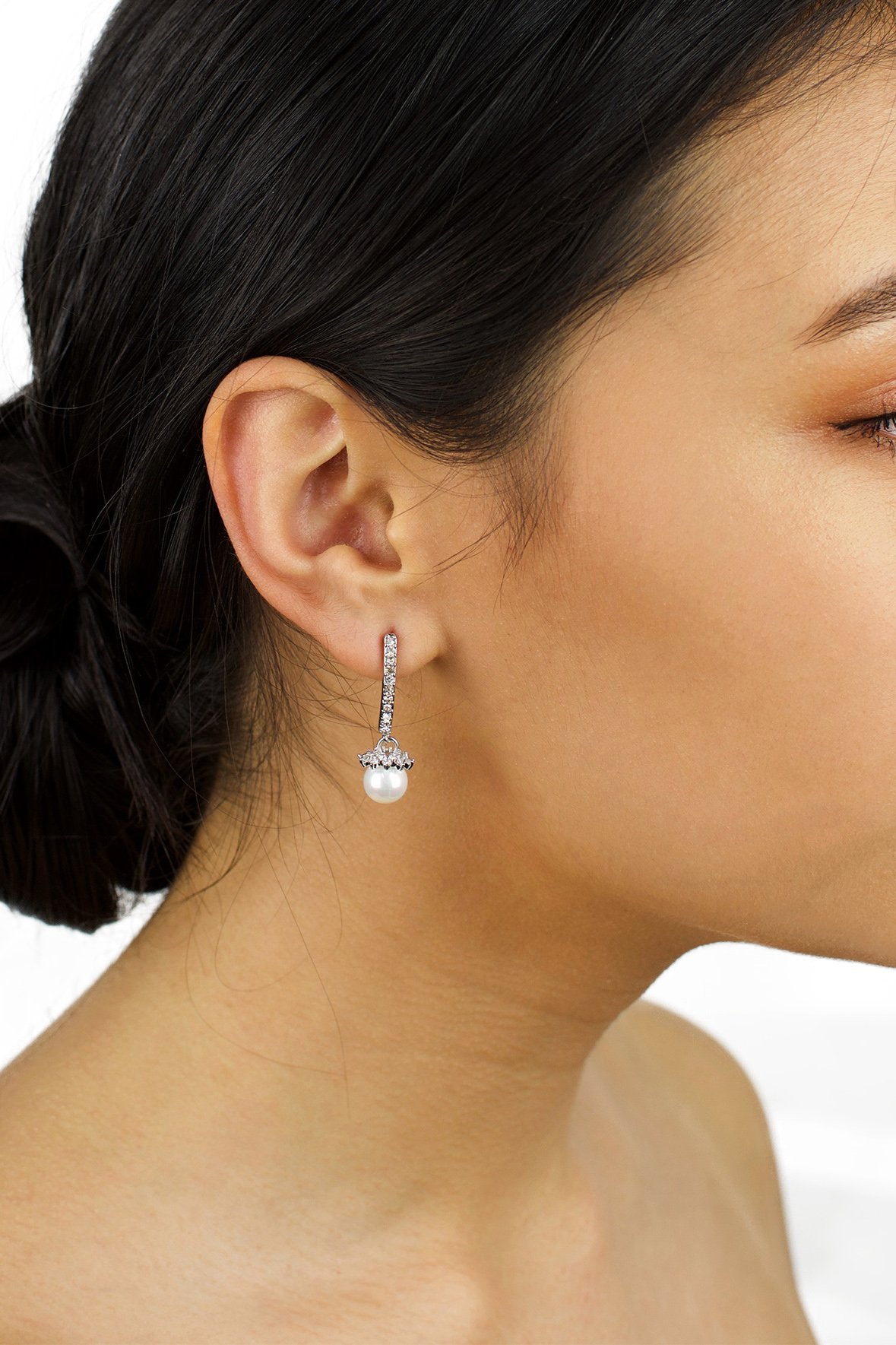 A dark hair model with a drop pearl earring in her ear