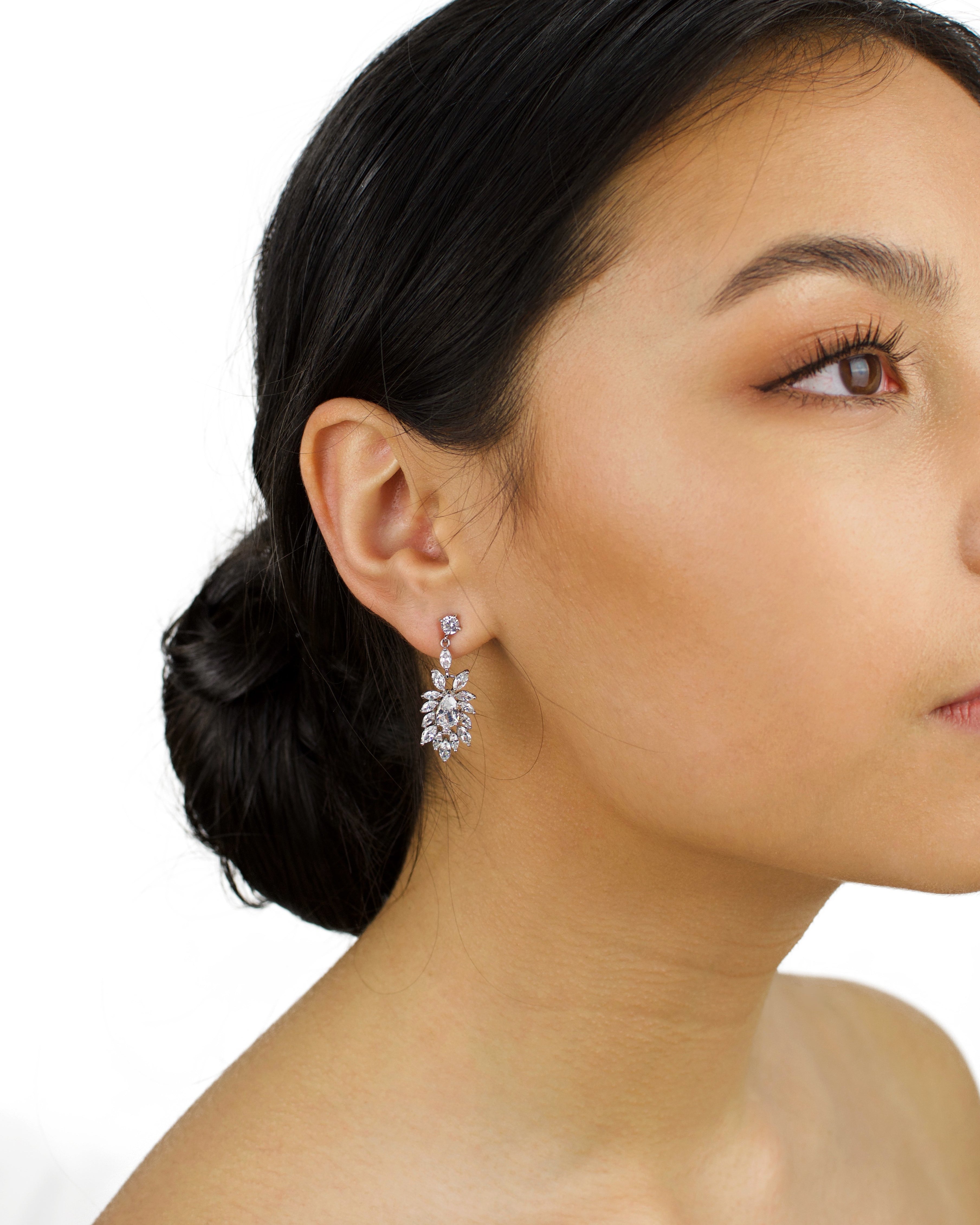 Model wears a silver earring with tiny stones. She has dark hair and a white background
