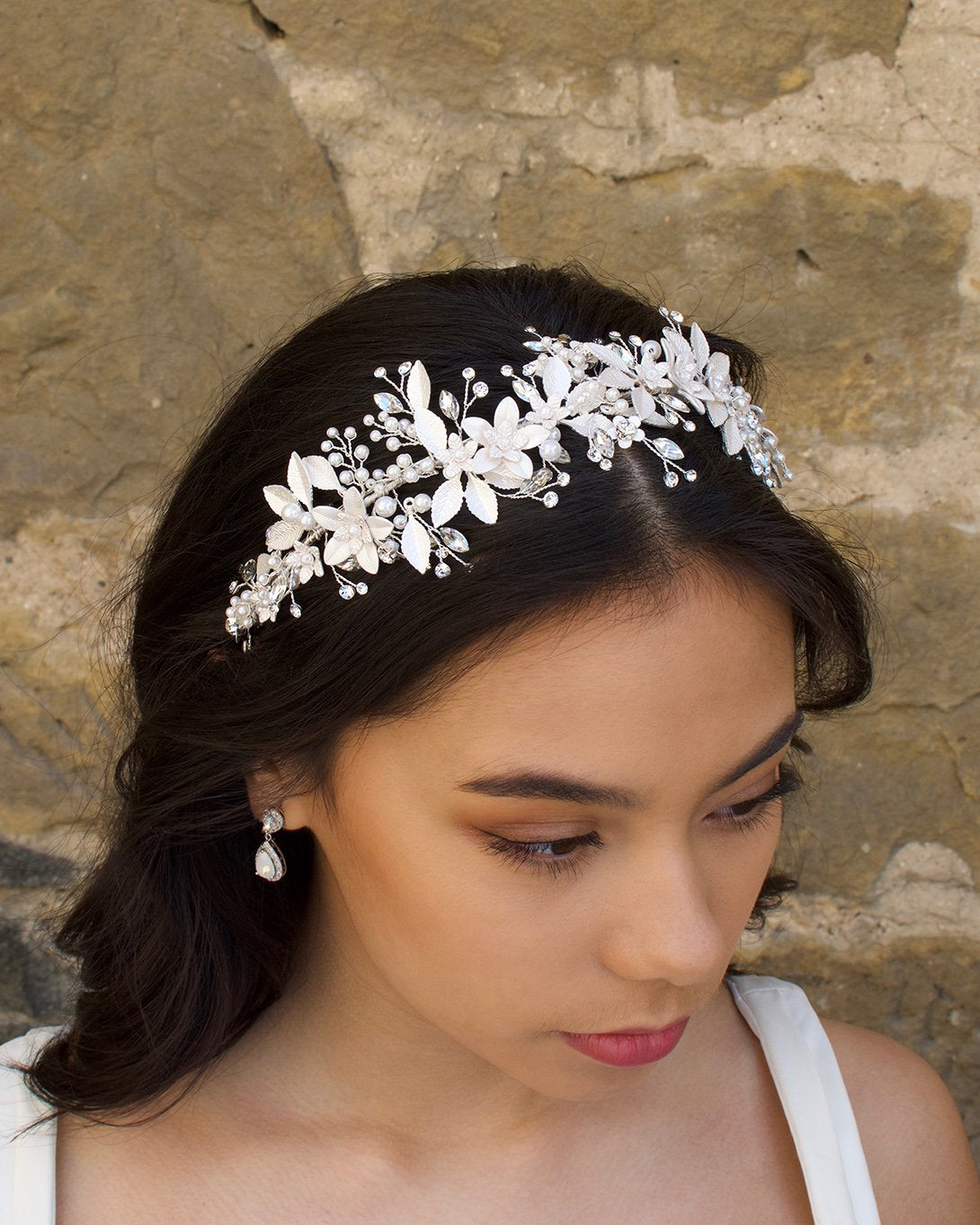 Black haired model wears a silver leaves headband with a wall backdrop