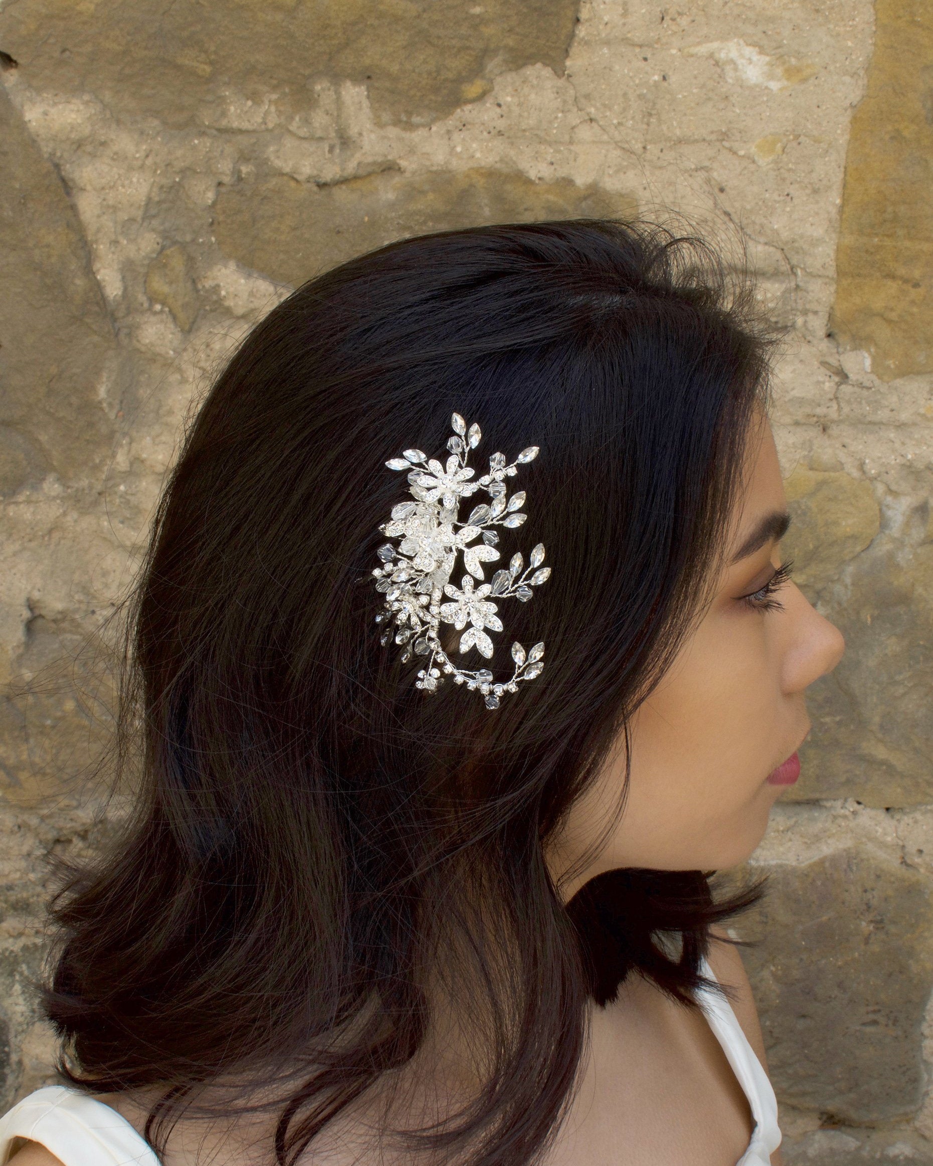 Silver Leaves and Crystals side comb worn by a dark haired model with a stone wall background