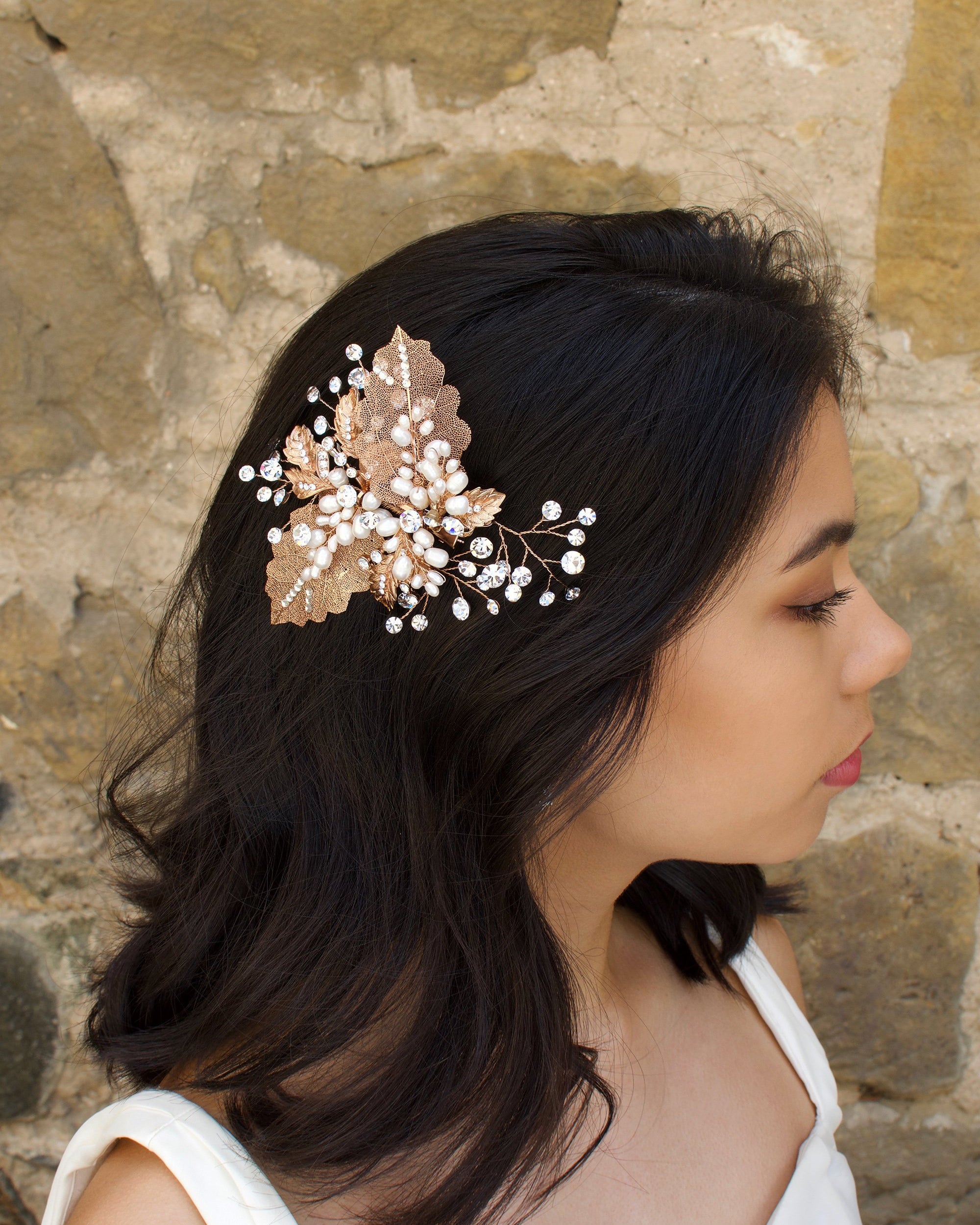 Filigree leaves side comb with freshwater pearls worn by a dark hair model in front of an old stone wall
