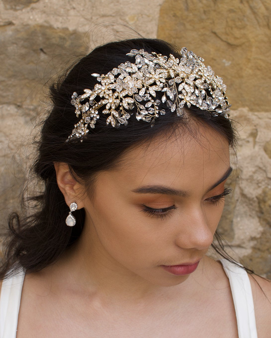 A model with dark hair wears a wide golden headband on the front of her head