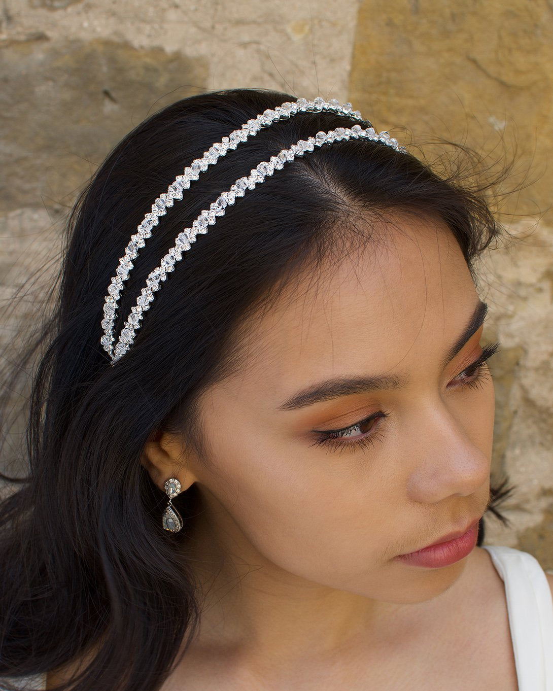 Black hair bride wearing a simple two row silver headband with a stone wall background.