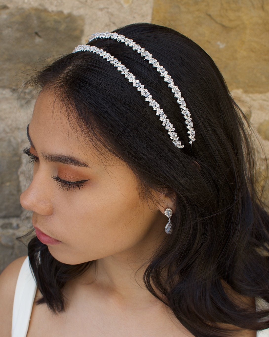 Dark hair model wears a two row bridal headband with a sandstone wall behind