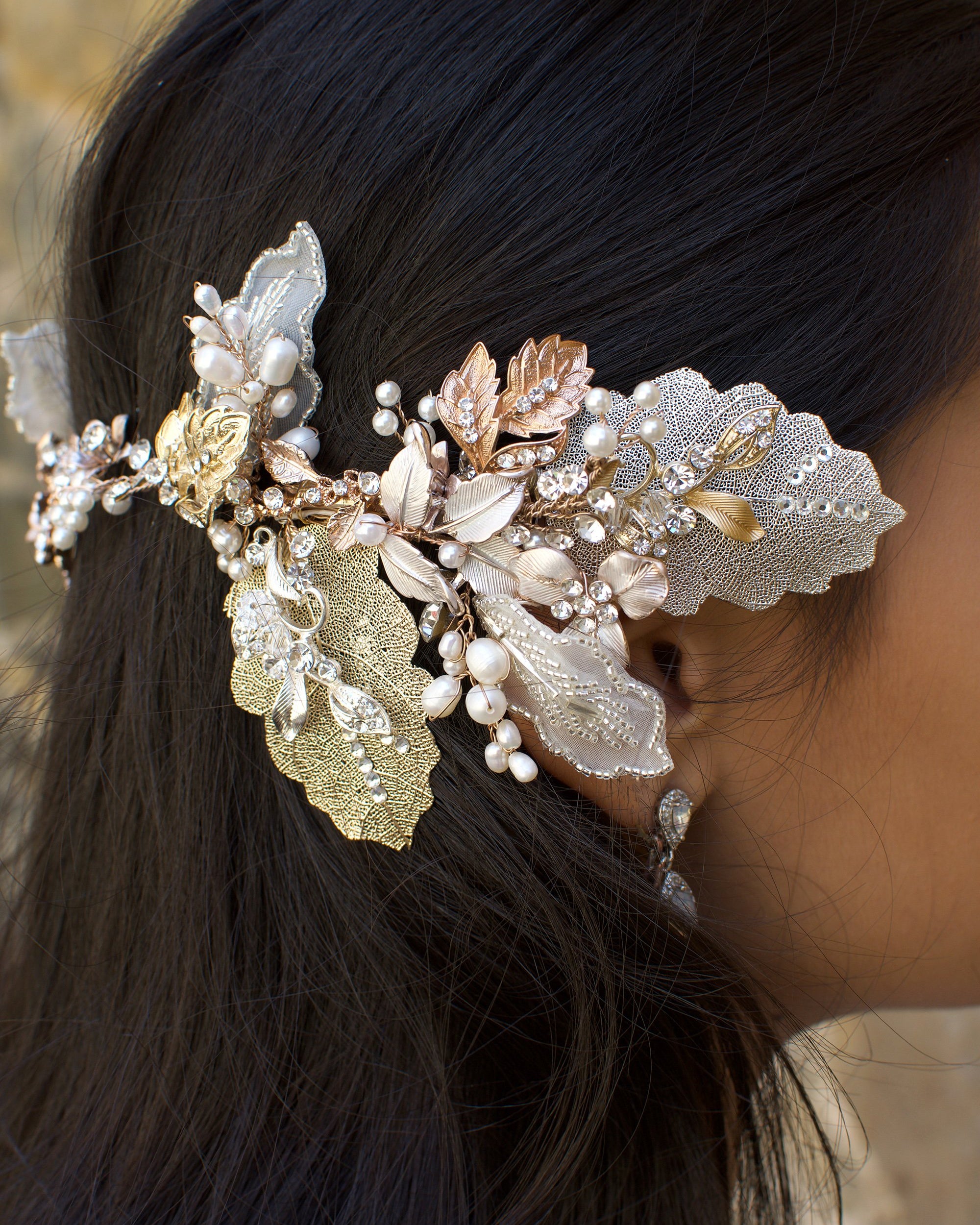 A dark haired model with hair down wears a Bridal Vine in Silver, Gold and Rose Gold with a background of stone