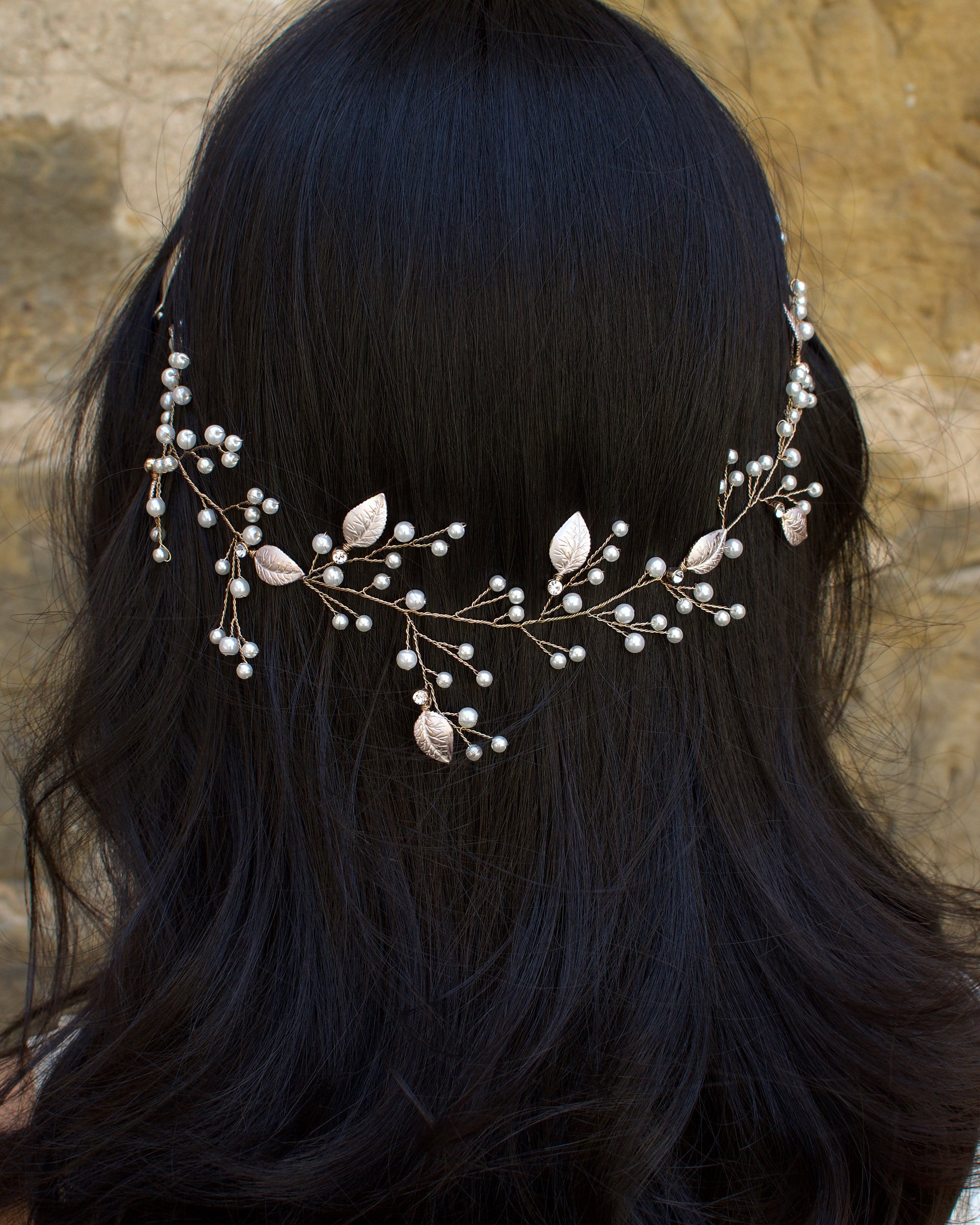 The back of a black haired model wearing a very fine wire bridal vine with leaves and pearls