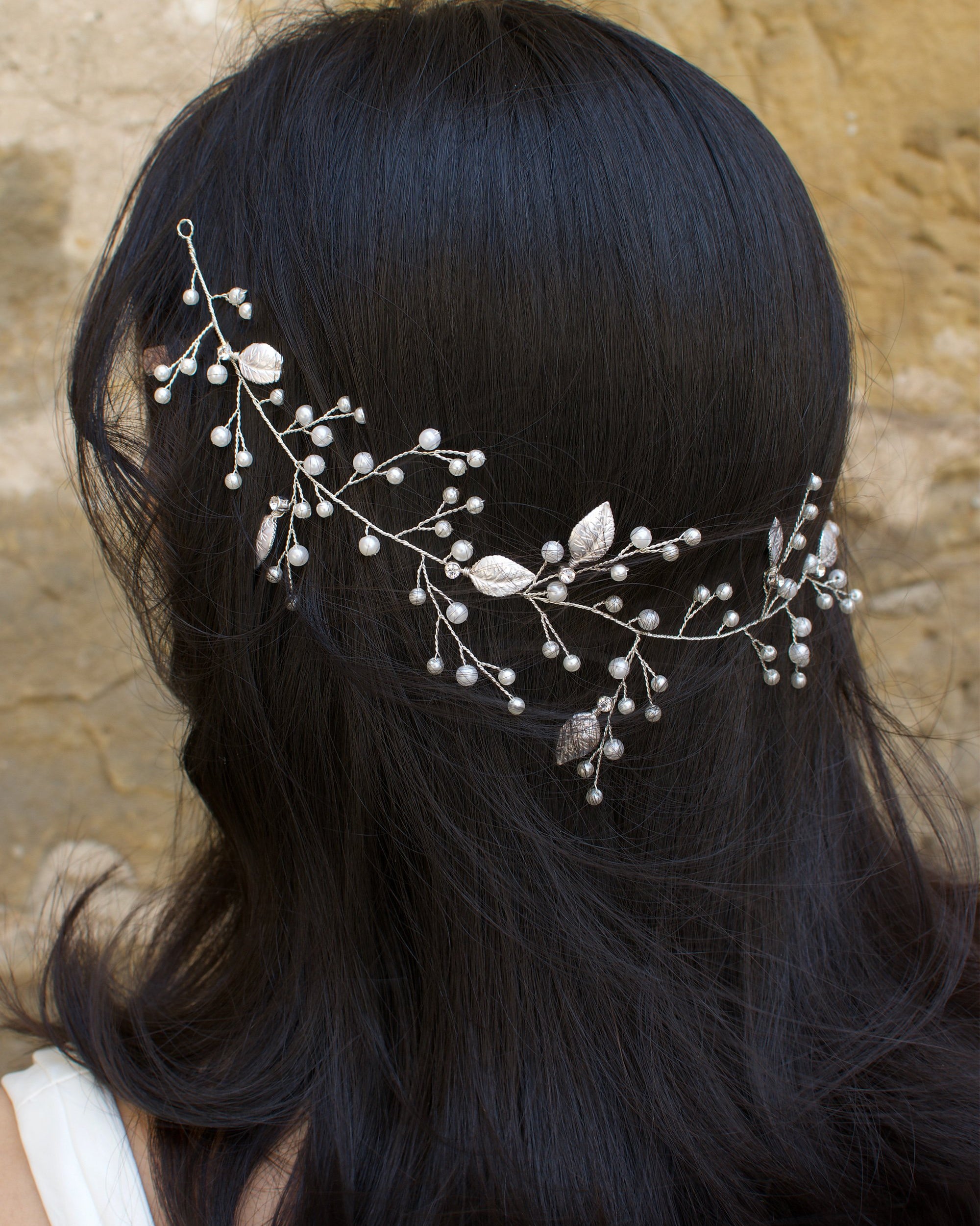 A black hair model wears a silver bridal vine on the back of her head with leaves and pearls