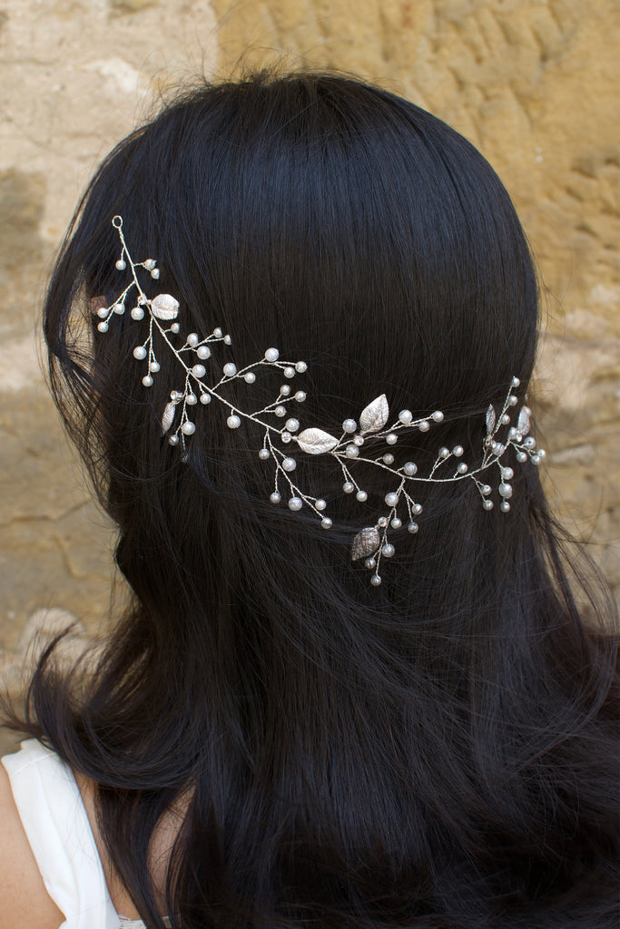 A black hair model wears a silver bridal vine on the back of her head with leaves and pearls