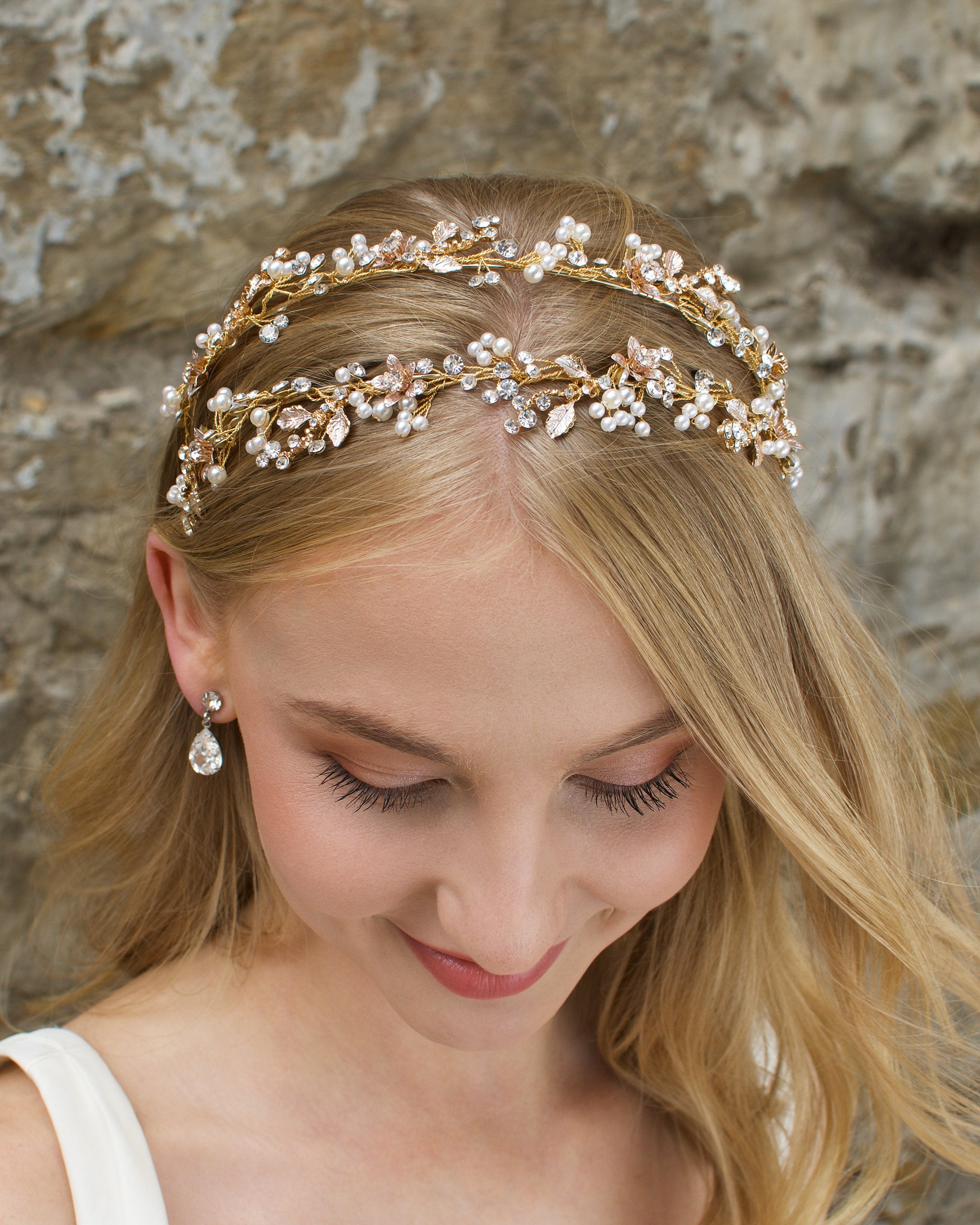Smiling Blonde Bride wears a headband in gold with a stone wall backdrop