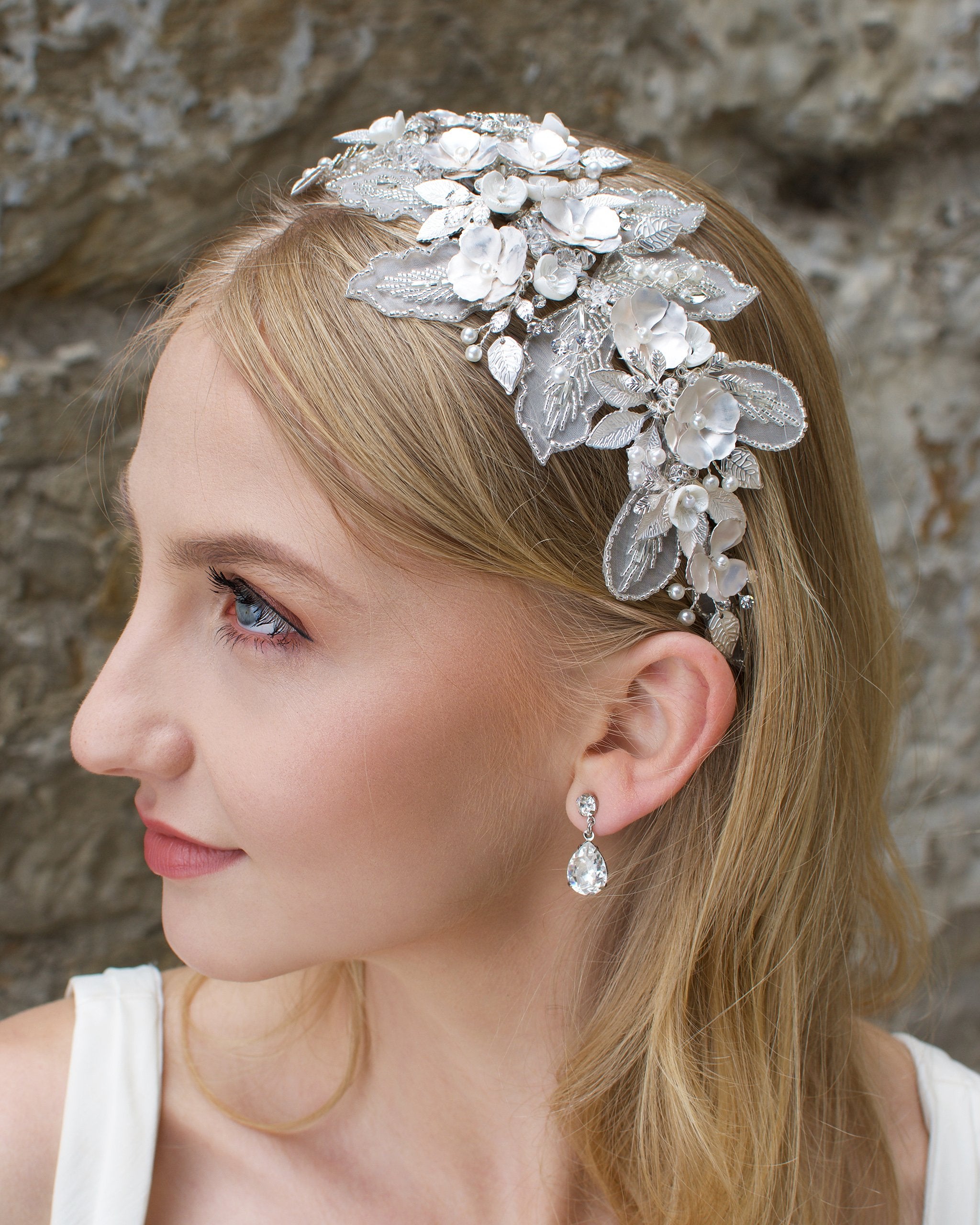 Blonde bride wearing a lace and flower headband with a stone wall backdrop