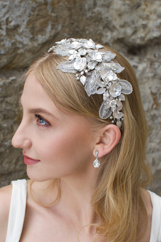 Blonde bride wearing a lace and flower headband with a stone wall backdrop