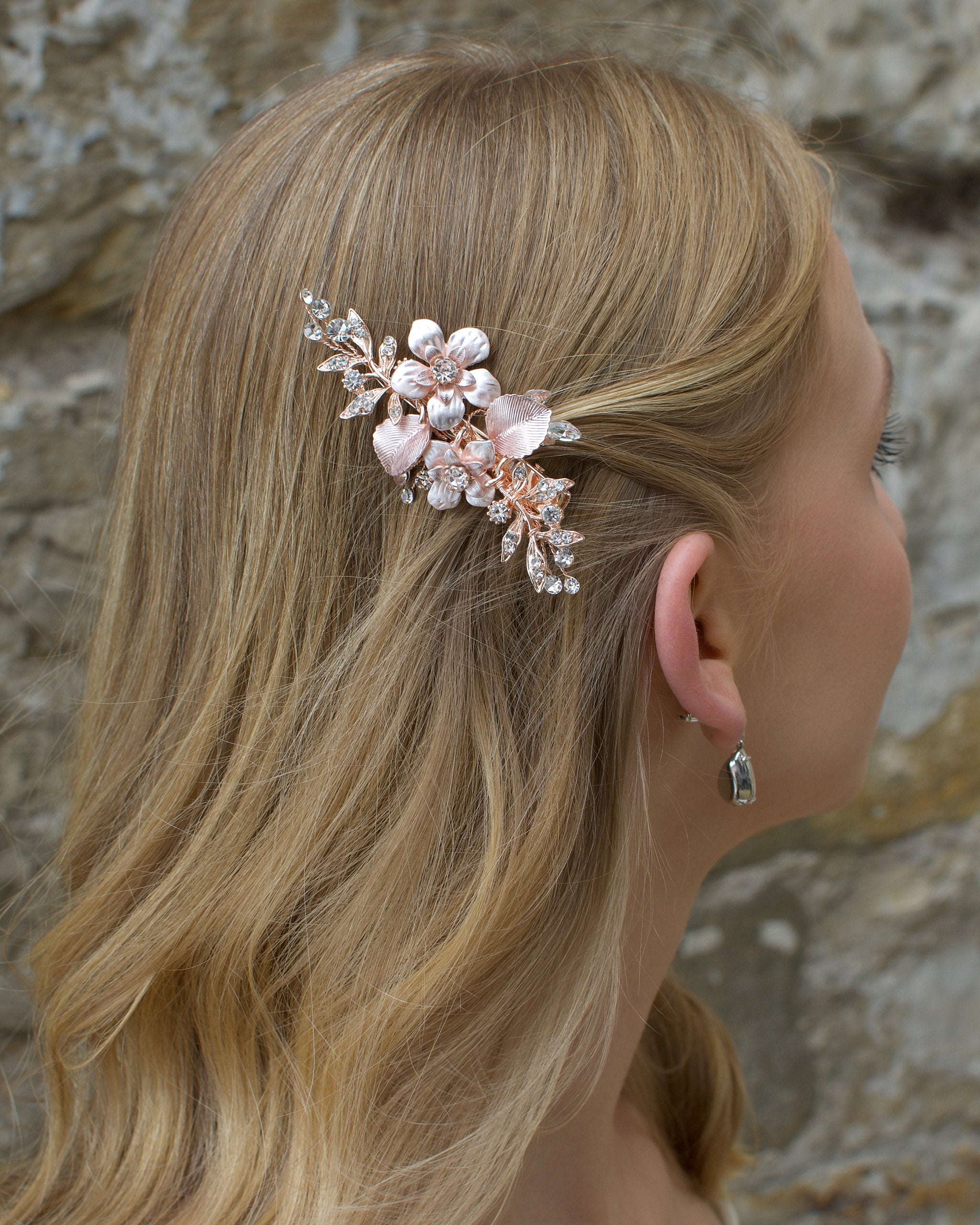 Pale Rose Gold clip worn by a blonde bride in front of an old stone wall