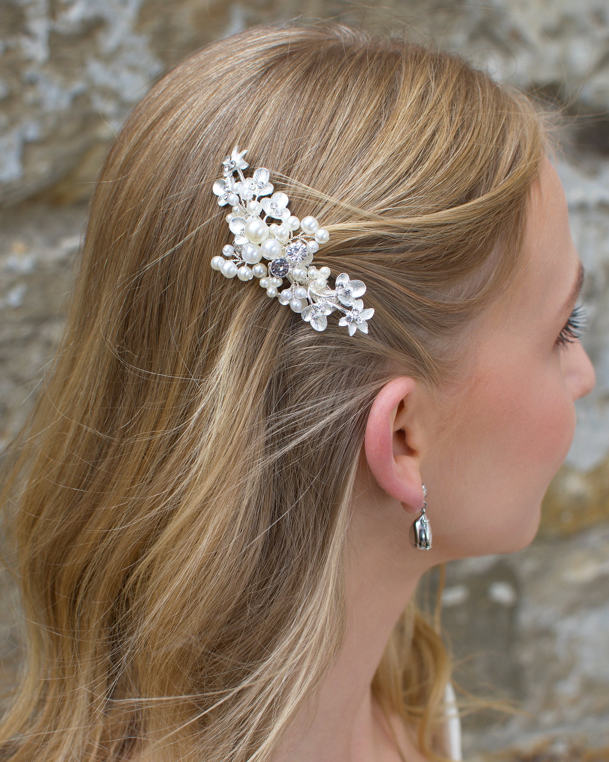 Blonde hair bride wears pearl and silver bridal side comb on the side of her head.