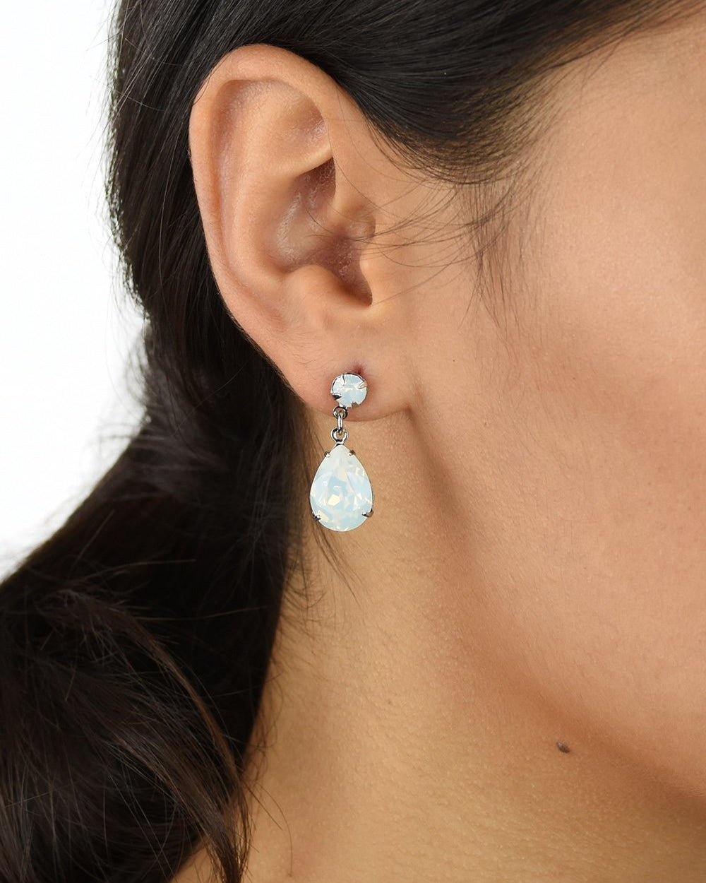 Dark hair model wears a silver earring with a white opal stone