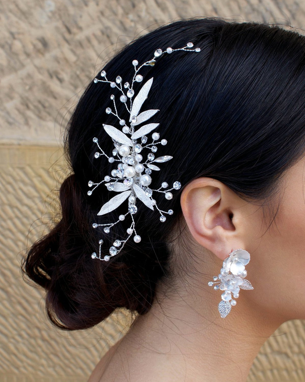 Dark hair Bride wearing a silver and leaf comb at the back of her head with a matching earring.