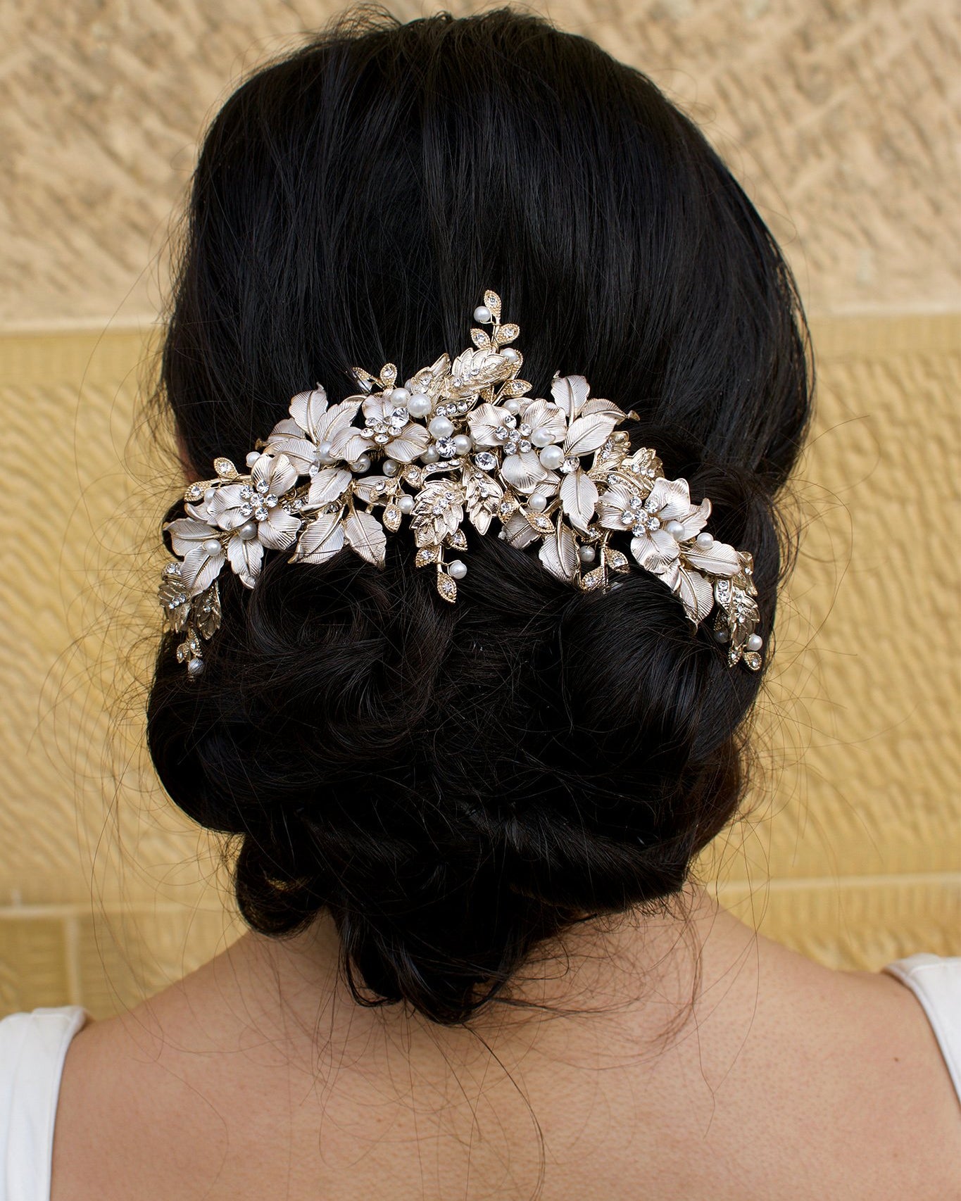 A Thick Pale Gold Short Bridal Vine on a dark hair model at the back of the head with a sandstone backdrop